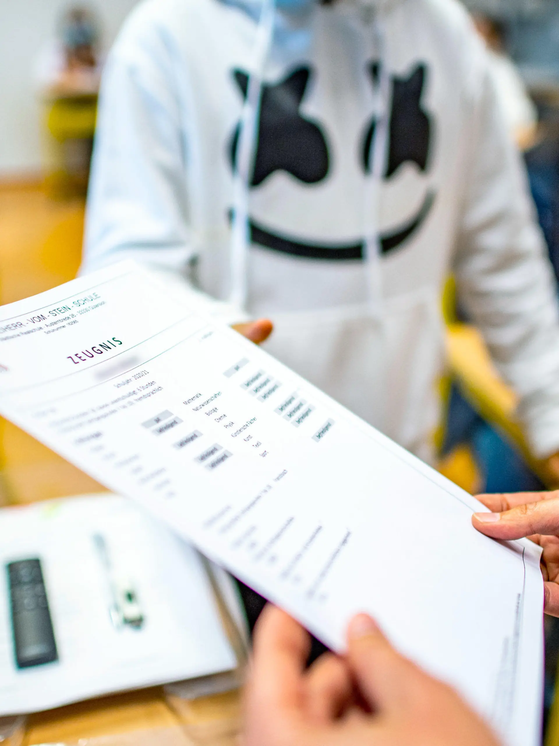 02.07.2021, Nordrhein-Westfalen, Gütersloh: Die Klassenlehrerin übergibt das Zeugnis eines Schülers der Klasse 9b der Freiherr-vom-Stein-Schule in Gütersloh. An den 5400 Schulen in Nordrhein-Westfalen ist am heutigen Freitag der letzte Schultag vor den Sommerferien. 2,5 Millionen Jungen und Mädchen bekommen ihre Zeugnisse. Foto: David Inderlied/dpa +++ dpa-Bildfunk +++