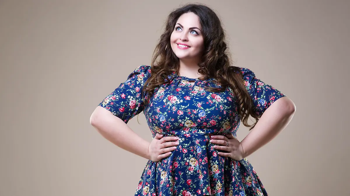 Plus size fashion model in casual clothes, fat woman on beige studio background, overweight female body, professional make-up and hairstyle
