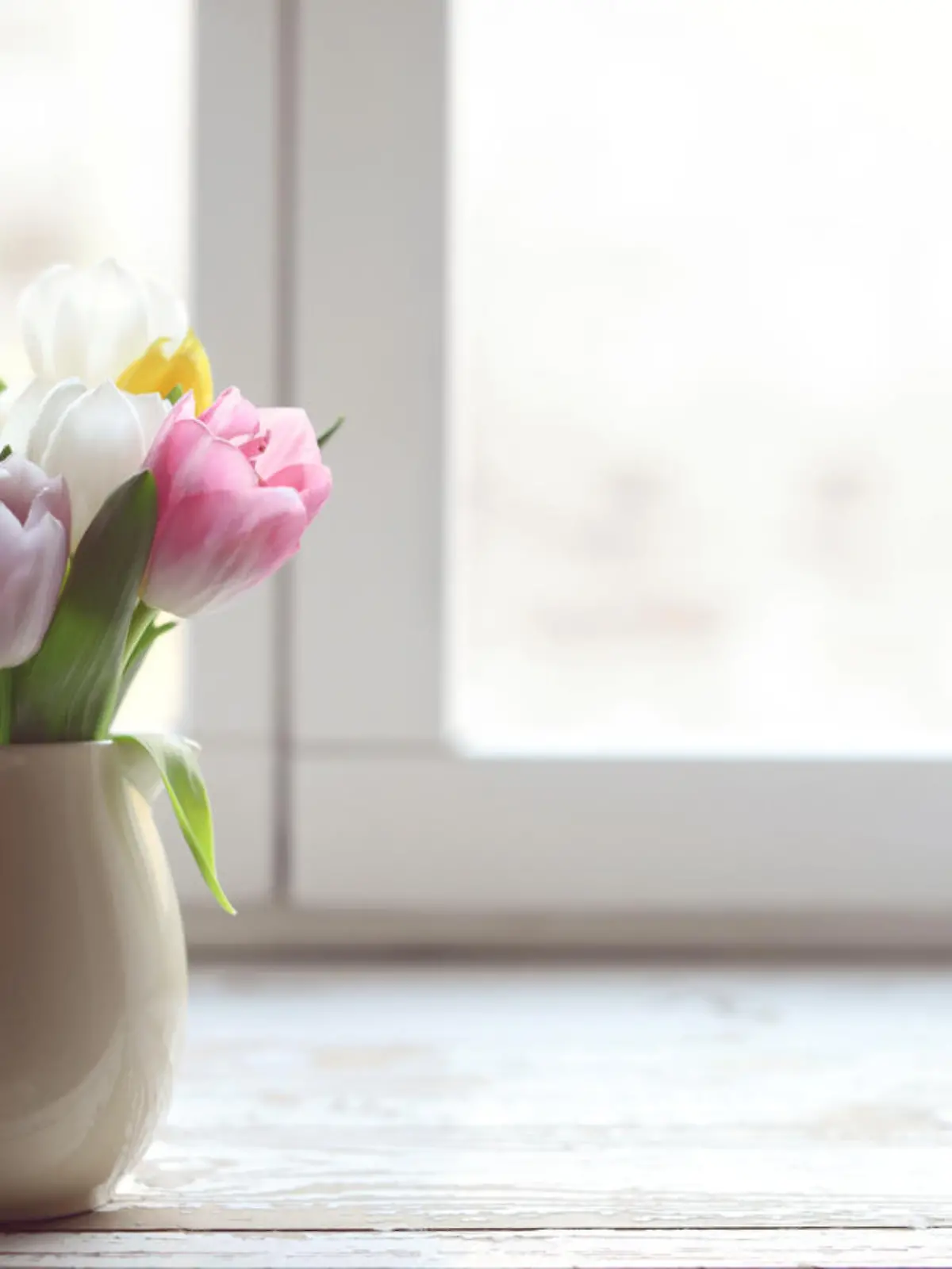 bouquet of tulips in a vase on a window sill at the window