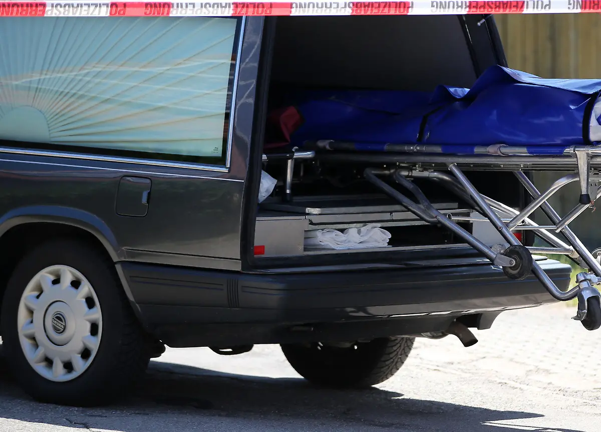 Bestatter schieben am 10.07.2015 in Leutershausen bei Ansbach (Bayern) einen Sarg in einen Leichenwagen. Ein Amokläufer hat dort mindestens zwei Menschen getötet. Die Polizei konnte den mutmaßlichen Täter kurz darauf festnehmen. Foto: Daniel Karmann/dpa +++(c) dpa - Bildfunk+++