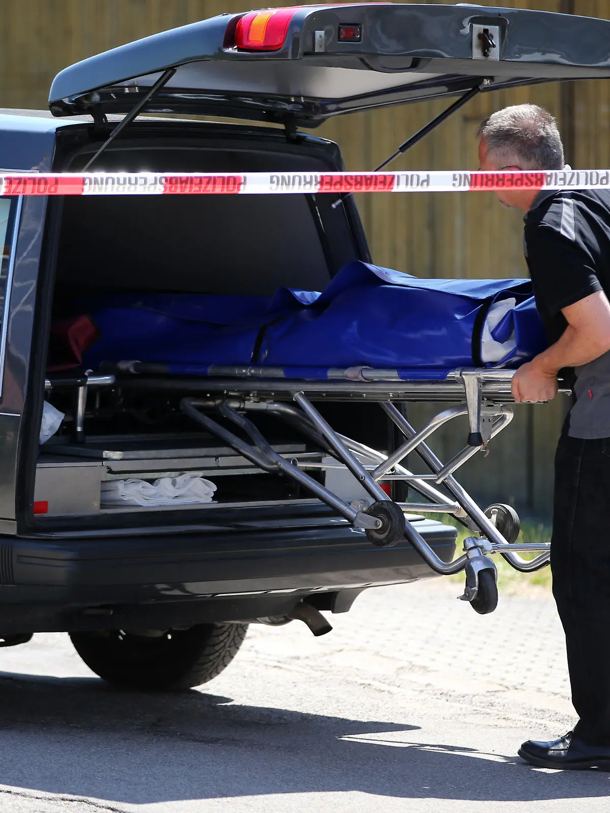 Bestatter schieben am 10.07.2015 in Leutershausen bei Ansbach (Bayern) einen Sarg in einen Leichenwagen. Ein Amokläufer hat dort mindestens zwei Menschen getötet. Die Polizei konnte den mutmaßlichen Täter kurz darauf festnehmen. Foto: Daniel Karmann/dpa +++(c) dpa - Bildfunk+++