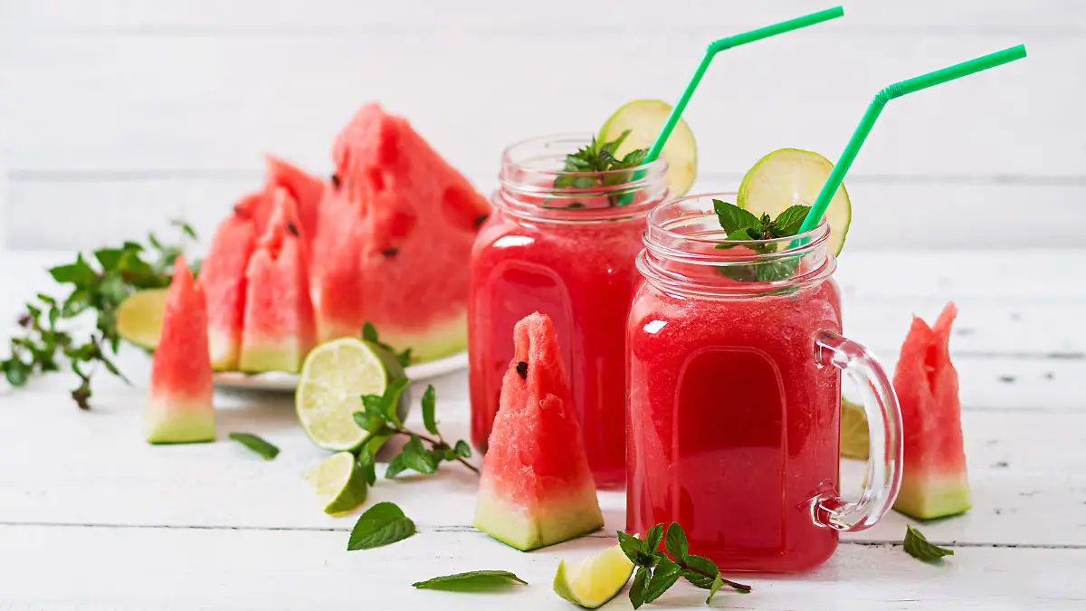 Fresh watermelon smoothies with lime and mint on white wooden background
