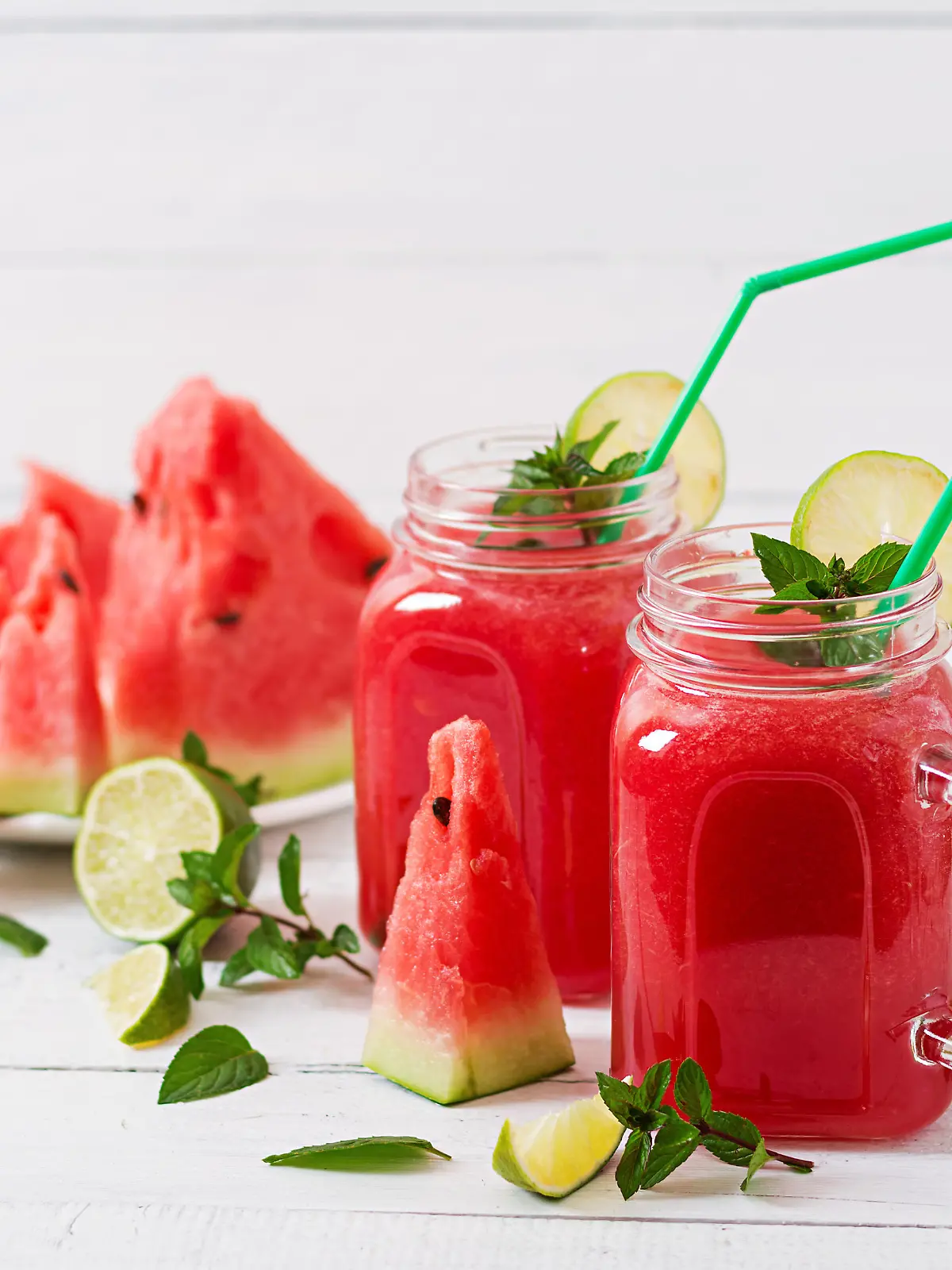 Fresh watermelon smoothies with lime and mint on white wooden background