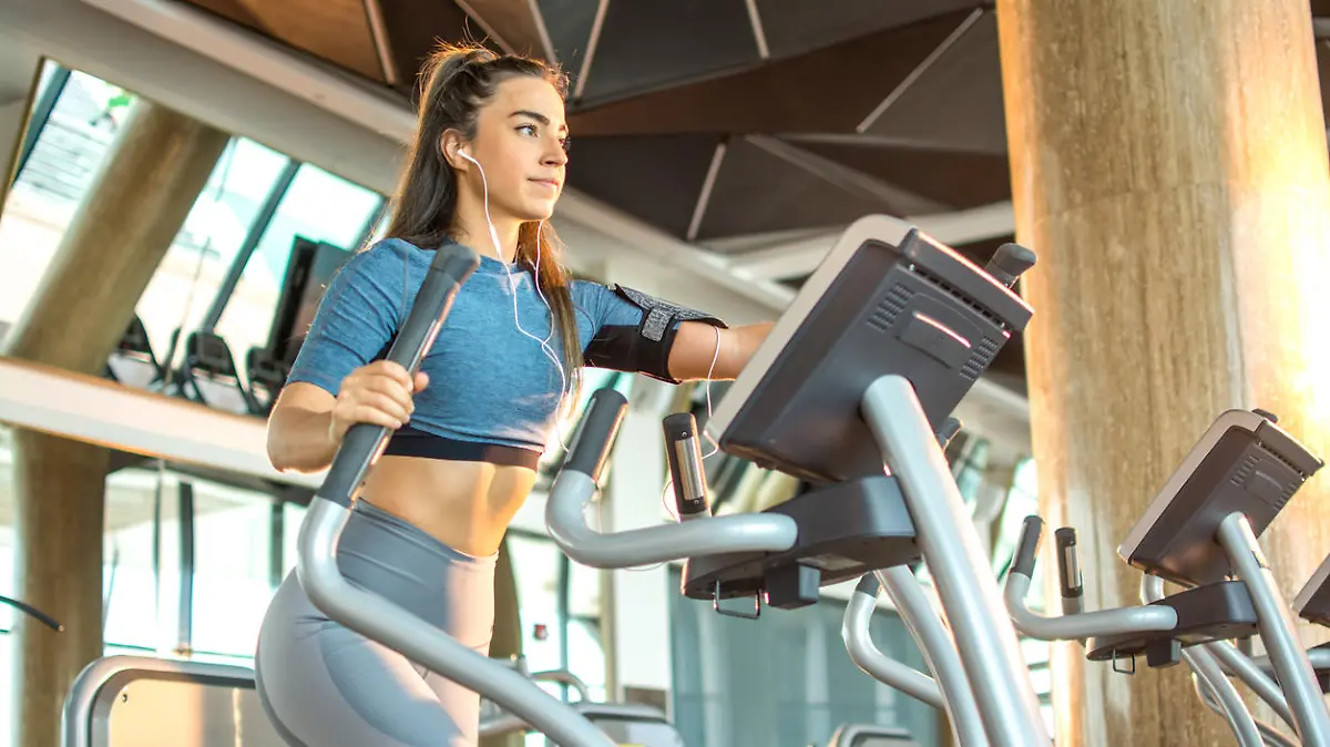 Attractive young fitness woman working out on an elliptical trainer in gym