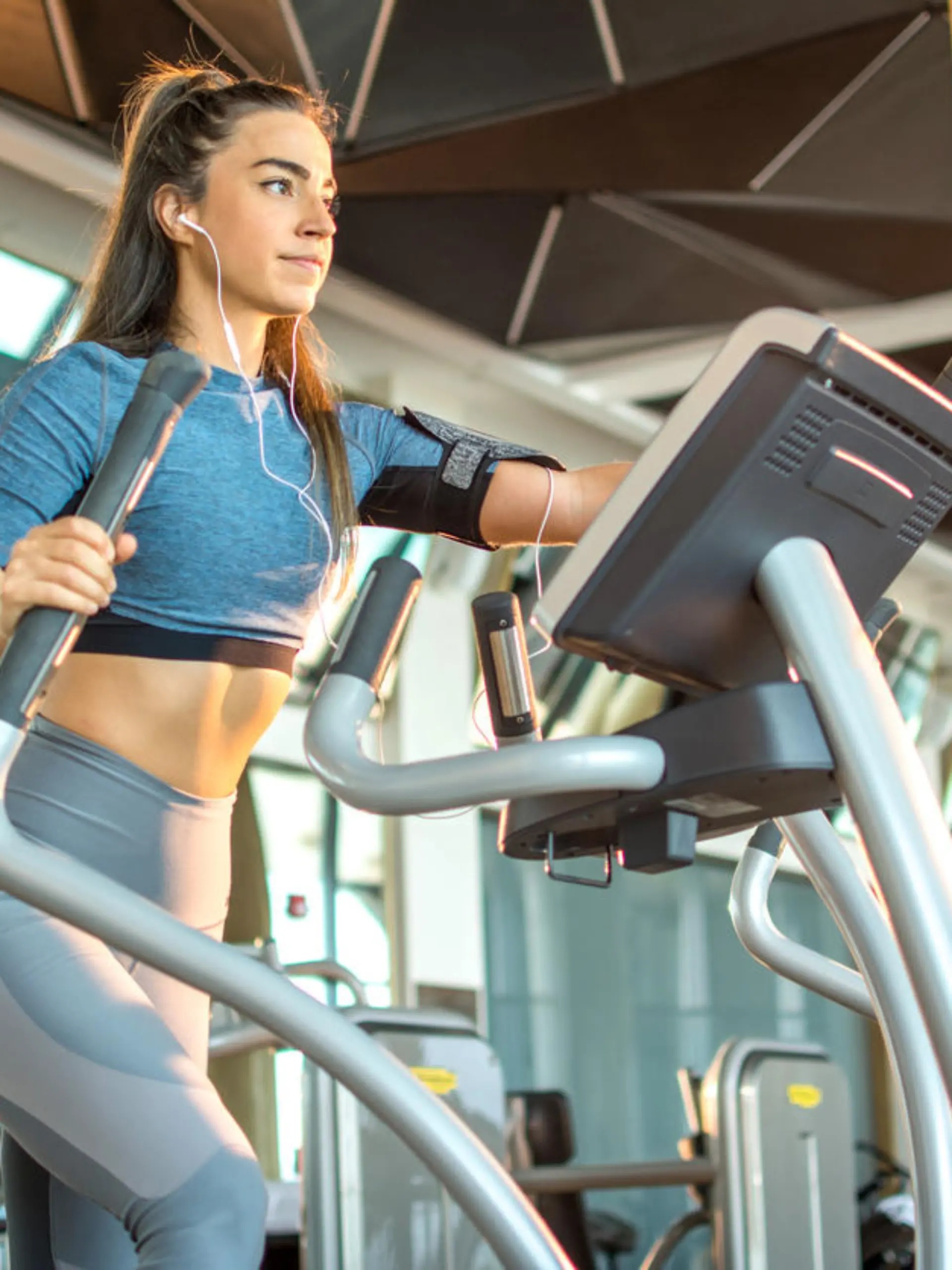 Attractive young fitness woman working out on an elliptical trainer in gym