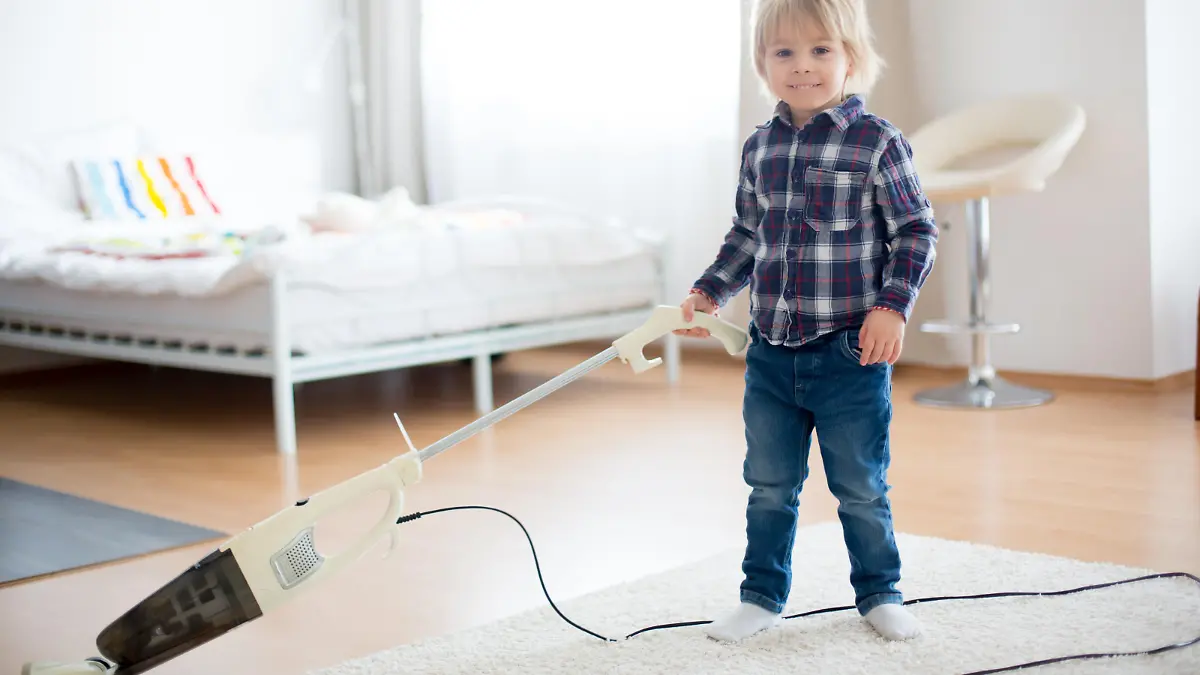 Cute little toddler child, boy, vacuum cleaning in living room at home