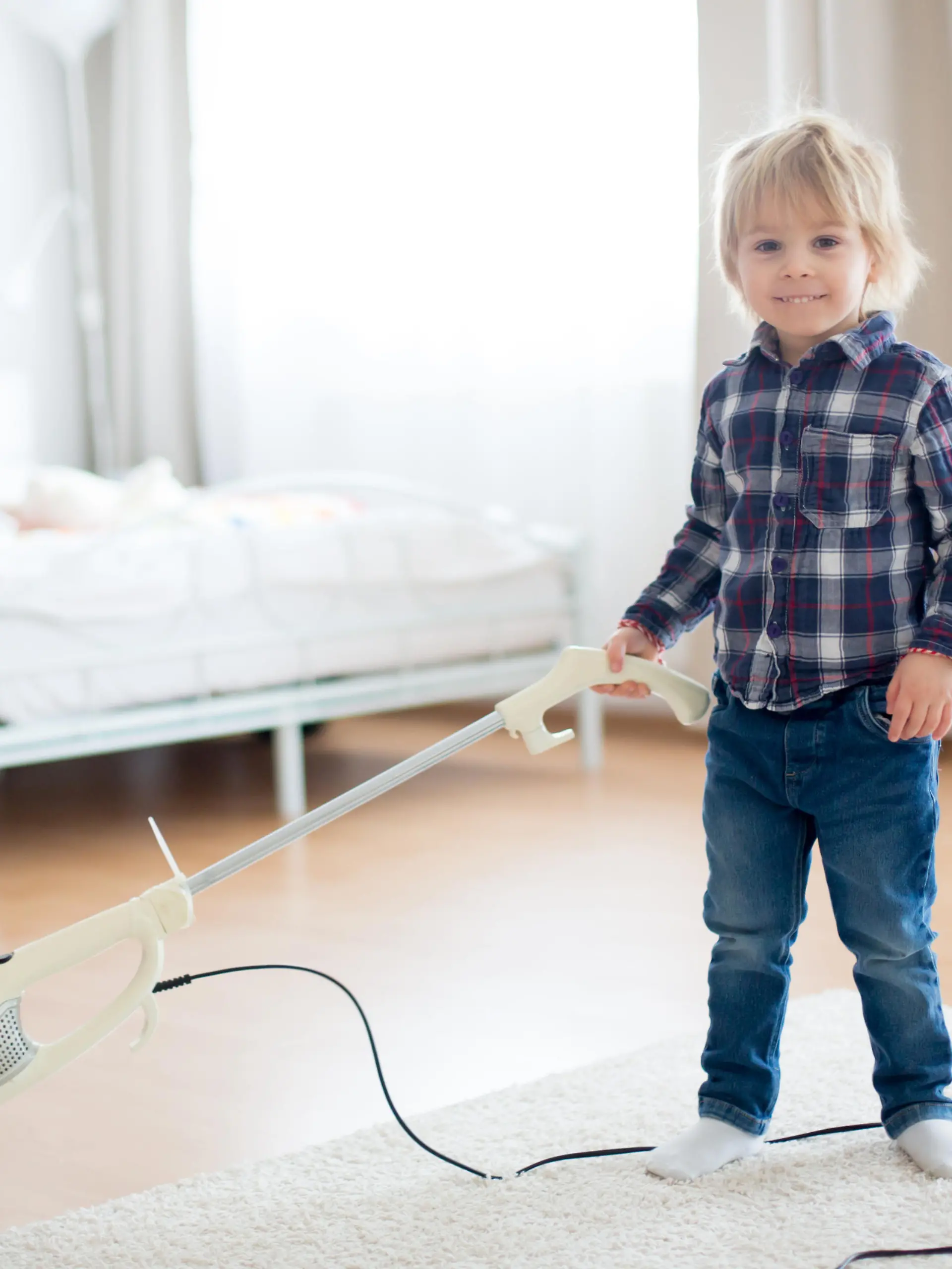 Cute little toddler child, boy, vacuum cleaning in living room at home