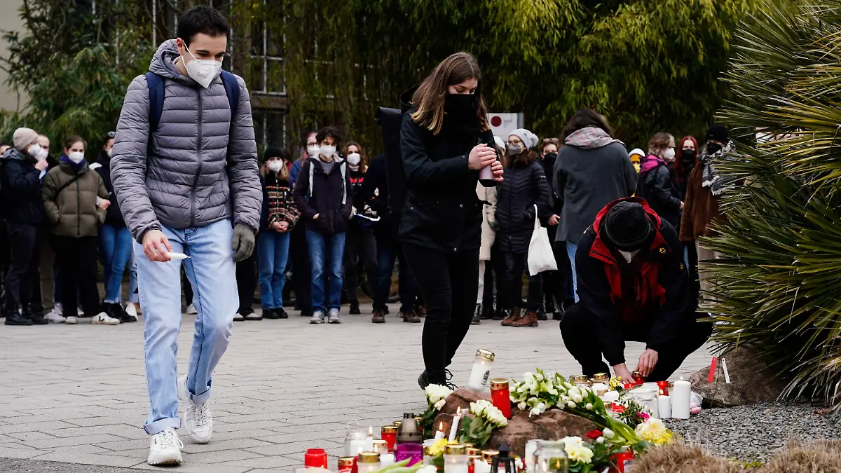 25.01.2022, Baden-Württemberg, Heidelberg: Menschen legen vor einem Gebäude der Universität Blumen und Kerzen an den Wegesrand. Gestern war ein 18 Jahre alter Student mit einer Schrotflinte bei laufender Vorlesung in den Hörsaal des Gebäudes gestürmt und hatte um sich geschossen. Eine junge Frau starb, der Täter tötete sich wenig später selbst. Foto: Uwe Anspach/dpa +++ dpa-Bildfunk +++