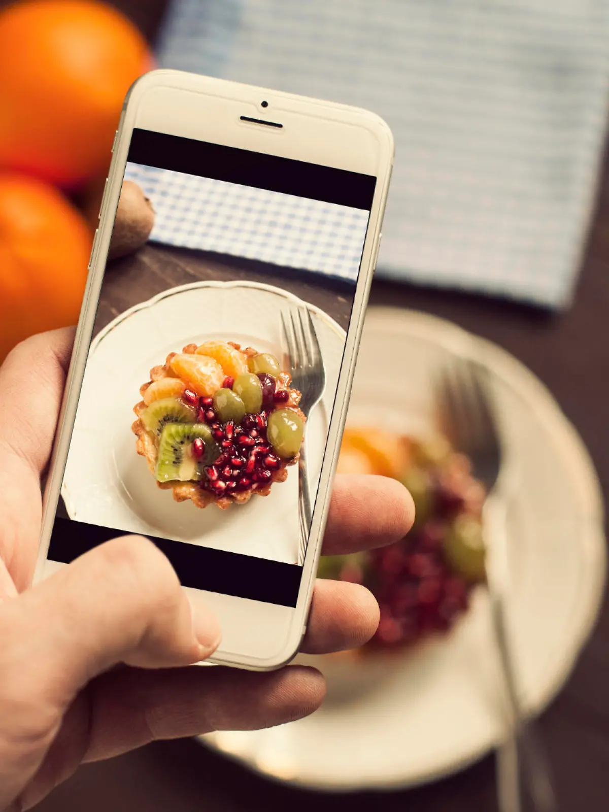 Fruit cake with, kivi, pomegranate, grapes, honey and tangerine. Taking photo of fruit cake. Toned photo