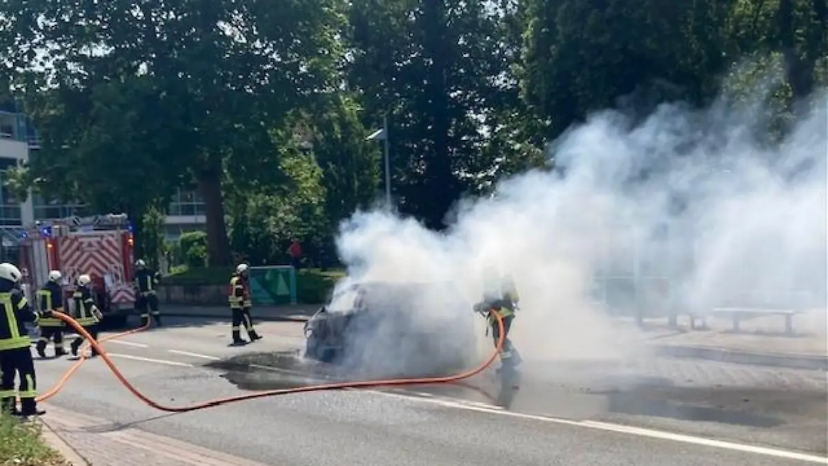 Feuerwehrleute löschen ein brennendes Fahrzeug