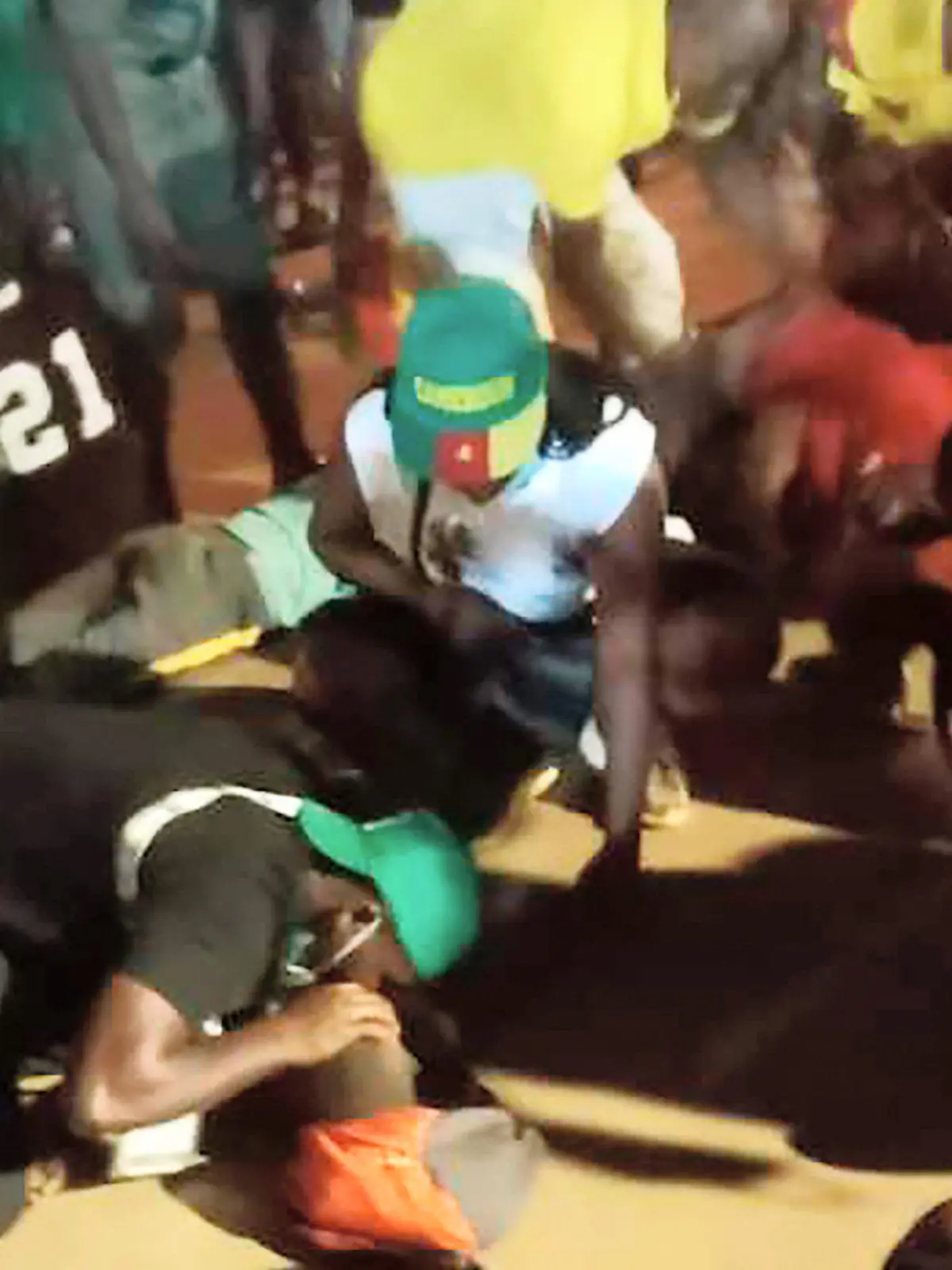 24.01.2022, Kamerun, Yaounde: Menschen helfen den Opfern einer Massenpanik vor einem Stadion, in dem ein Fußballspiel des Afrikanischen Nationen-Pokals in Yaounde, Kamerun, ausgetragen wird. Mehrere Menschen starben bei einer Massenpanik, die sich ereignete, als die Menschenmenge darum kämpfte, Zugang zum Olembe-Stadion zu erhalten, um das Achtelfinalspiel des Gastgebers gegen die Komoren im Rahmen des wichtigsten afrikanischen Fußballturniers zu sehen. (Wiederholung mit verändertem Bildausschnitt) Foto: Thierry Noukeu/AP/dpa +++ dpa-Bildfunk +++