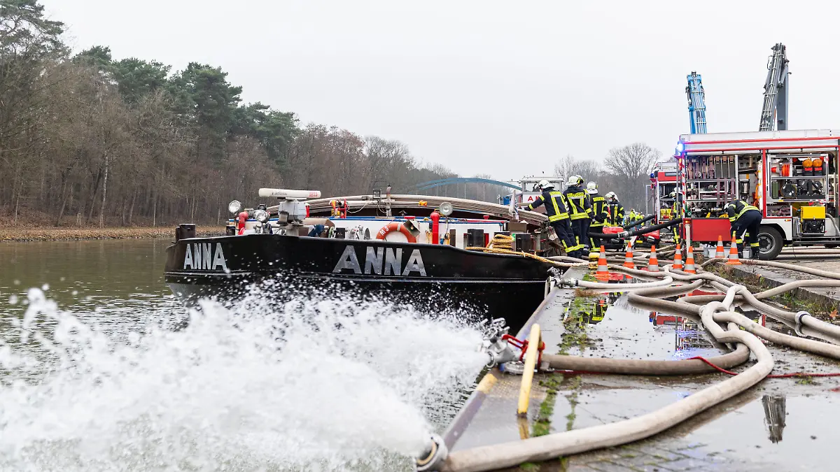 25.01.2022, Niedersachsen, Spelle: Die Feuerwehr pumpt ein mit Wasser vollgelaufenes Binnenschiff, dass an einer Keilmauer auf dem Dortmund-Ems Kanal liegt mit insgesamt vier Pumpen leer. Treibstoff ist aus dem Dieseltank des 80m langen Schiffs ausgelaufen und Wasser ist in den Laderaum eingedrungen, wobei das Schiff mit dem kompletten Bug unter Wasser stand. Foto: Guido Kirchner/dpa +++ dpa-Bildfunk +++