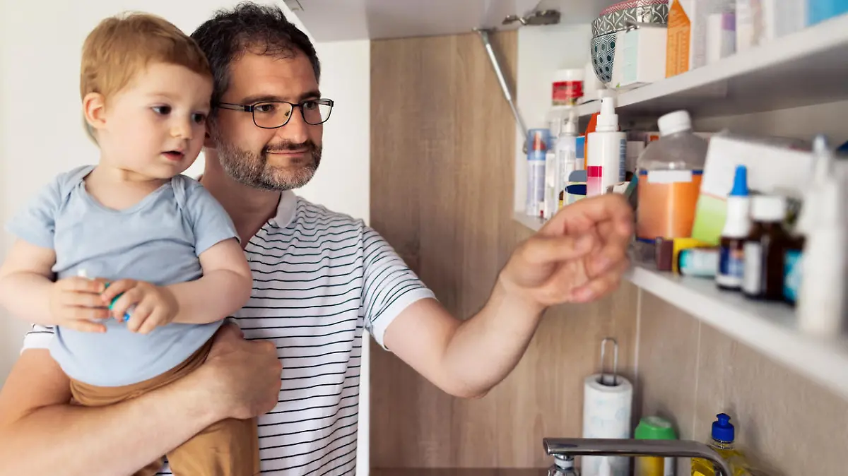Caucasian mature adult father and his baby son taking medicines out of medicine cabinet at home.