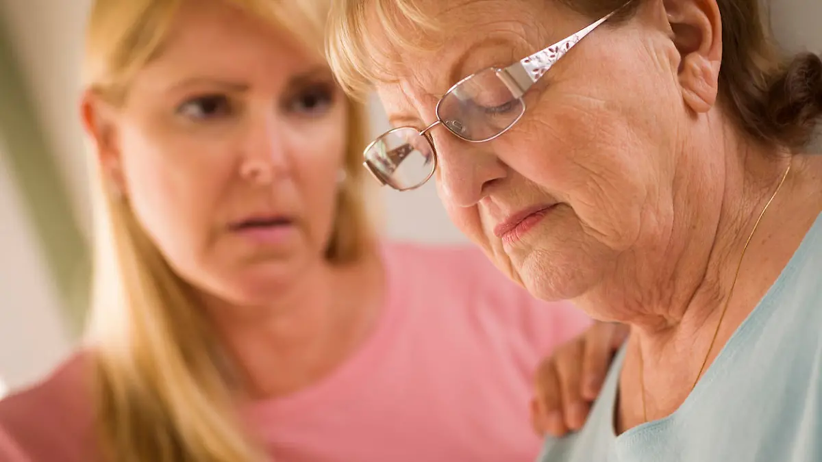 Young Adult Woman Consoles Sad Senior Adult Female.