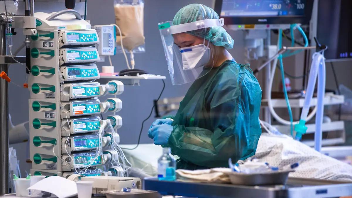 30.11.2021, Mecklenburg-Vorpommern, Rostock: Eine Intensivschwester betreut einen Patienten in einem der Behandlungszimmer der Intensivstation in der Universitätsmedizin Rostock. Angesichts der sprunghaft zunehmenden Zahl von Corona-Infizierten und der hohen Auslastung der Intensivstationen hat die Universitätsmedizin einen Covid-Ethikbeirat gebildet. Auch Patienten aus Sachsen werden in der Klinik behandelt. Foto: Jens Büttner/dpa-Zentralbild/dpa +++ dpa-Bildfunk +++