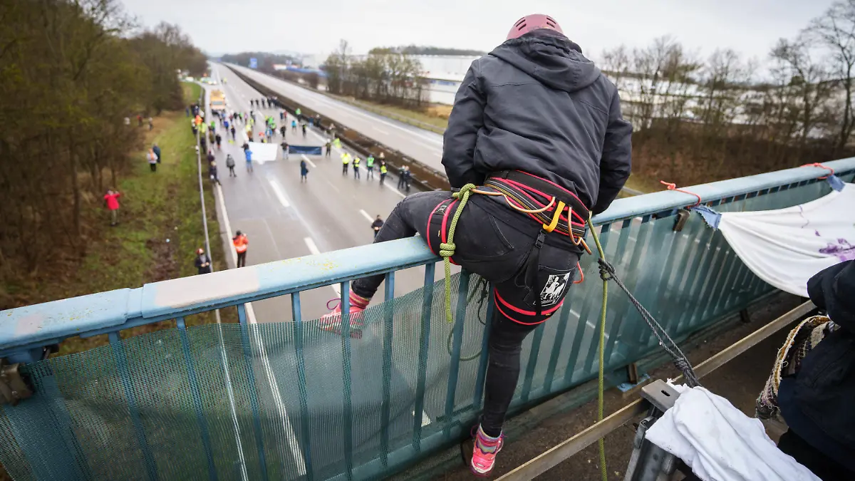 23.01.2022, Hessen, Künzell: Ein Aktivistin klettert über das Geländer einer Brücke über die gesperrte Fahrbahn der Autobahn A7 am Rande von Künzell bei Fulda. Mit der genehmigten Abseilaktionktion soll für eine echte Verkehrswende, den sofortigen Stopp des Straßenbaus, einen konsequenten Klimaschutz und gegen Strafen für Autobahnaktionen geworben werden. Foto: Frank Rumpenhorst/dpa/Frank Rumpenhorst/dpa +++ dpa-Bildfunk +++