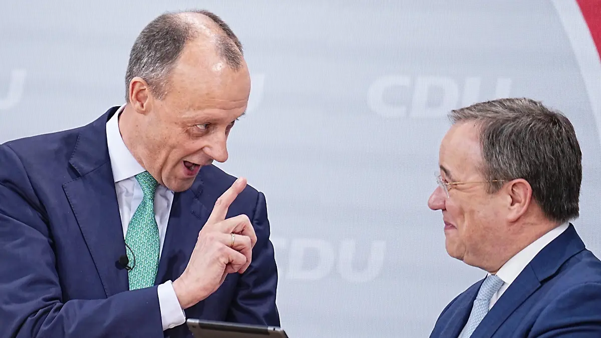 22.01.2022, Berlin: Friedrich Merz (l), Kandidat für das Amt des CDU Bundesvorsitzenden, überreicht dem scheidenden CDU-Bundesvorsitzenden Armin Laschet beim Bundesparteitag der CDU im Konrad-Adenauer-Haus ein iPad mit speziellen Apps. Beim 34. Parteitag der CDU soll Merz als neuer Bundesvorsitzender gewählt werden. Pandemiebedingt findet der Parteitag rein digital statt. Das Ergebnis der Wahl muss daher noch per Briefwahl bestätigt werden. Foto: Michael Kappeler/dpa +++ dpa-Bildfunk +++