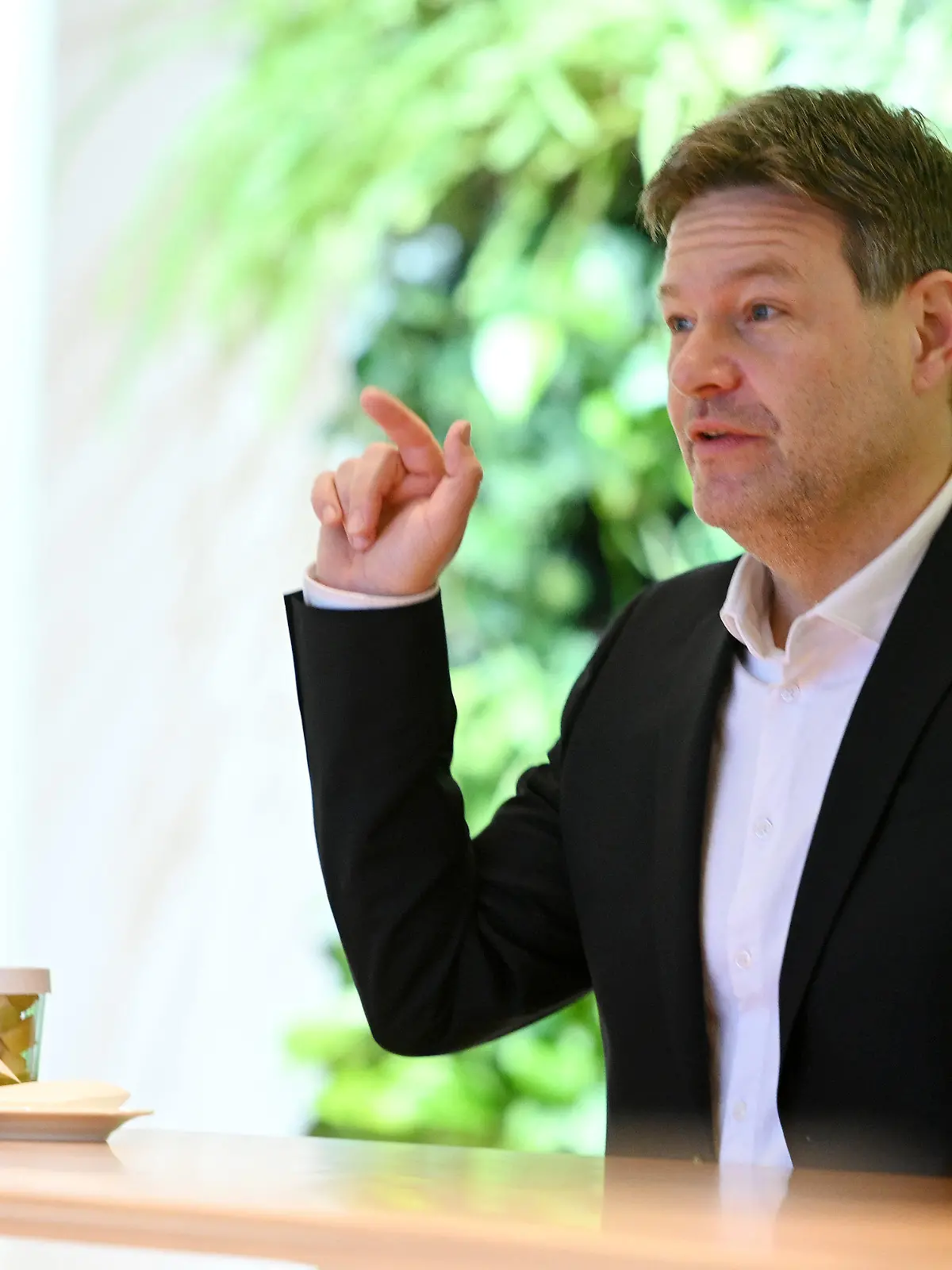 20.01.2022, Bayern, München: Robert Habeck (Bündnis 90/Die Grünen - r), Bundesminister für Wirtschaft und Klimaschutz, sitzt in der Staatskanzlei am Tisch und gestikuliert. Habeck kam mit dem bayerischen Ministerspräsidenten zu Gesprächen zusammen. Ein wichtiges Thema bei Habecks Treffen mit bayerischen Regierungsvertretern werden die strengen Abstandsregelungen für Windräder in Bayern sein, die den Ausbau der Windkraft im Freistaat ausbremsen. Foto: Tobias Hase/dpa +++ dpa-Bildfunk +++