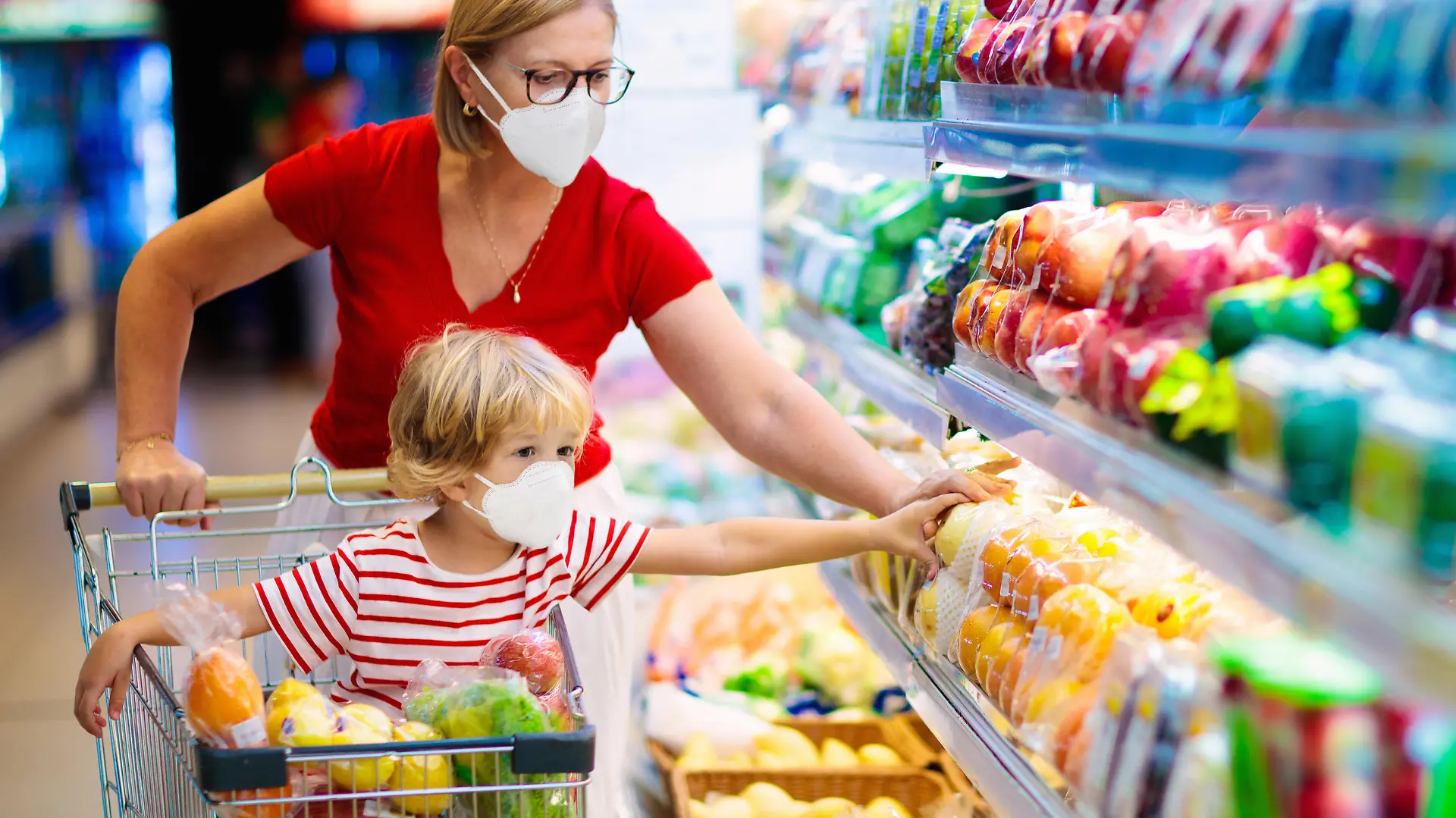 Shopping with kids during virus outbreak. Mother and child wearing surgical face mask buying fruit in supermarket. Mom and little boy buy fresh vegetable in grocery store. Family in shop.