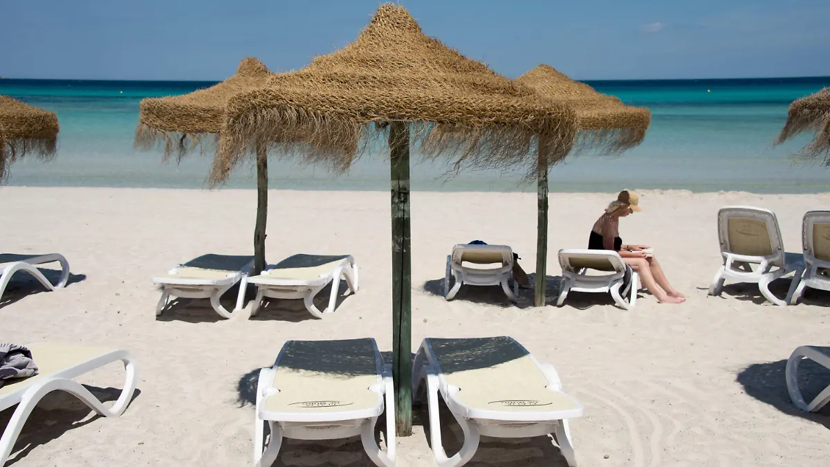 ARCHIV - 09.06.2013, Spanien, Muro: Eine Urlauberin sitzt am Strand an der Platja de Muro im Norden der Mittelmeerinsel. Reisewarnungen, verunsicherte Urlauber, Stillstand der Geschäfte und Ärger um Rückerstattung von Kundengeldern: Die Tourismusindustrie erlebt eine nie da gewesene Krise. (zu dpa «Jahr der Entscheidung - Krise von «epischen Dimensionen» im Tourismus») Foto: picture alliance / dpa +++ dpa-Bildfunk +++