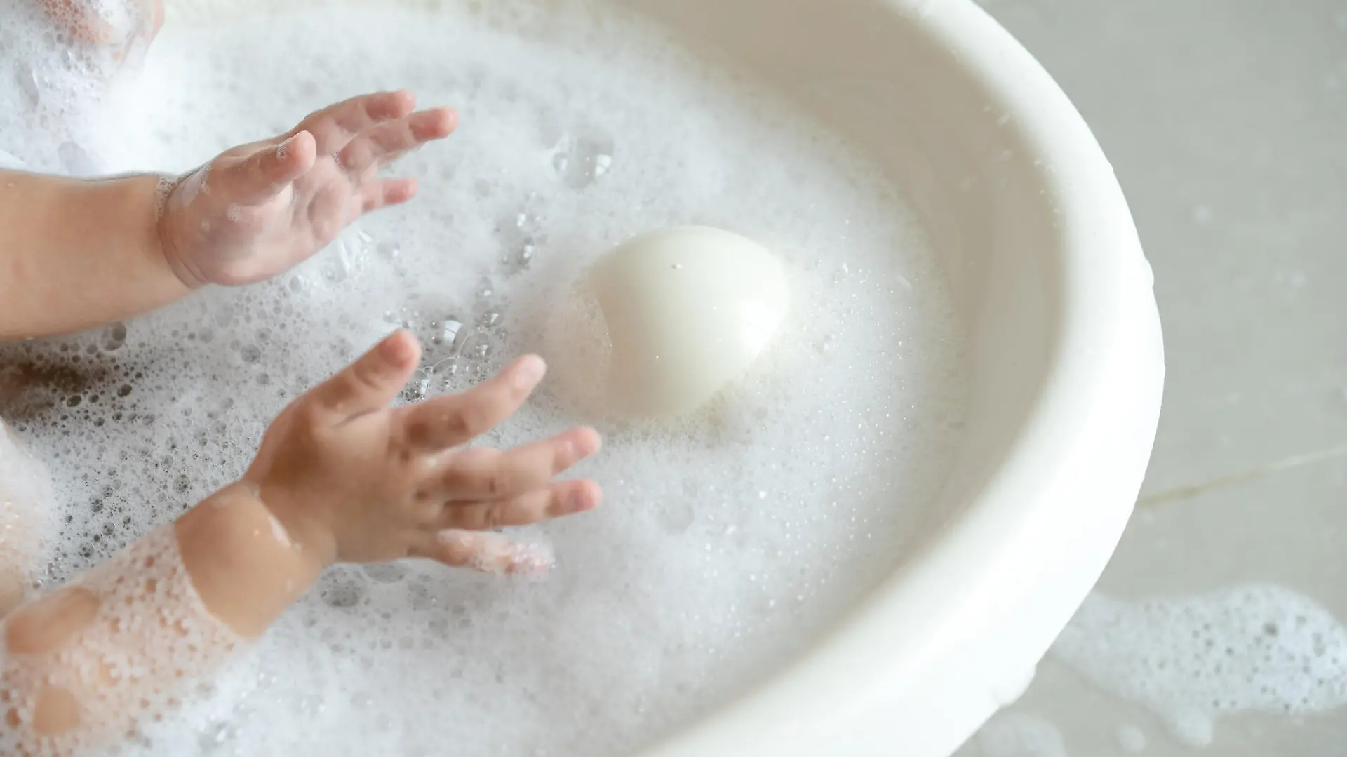 close up baby girl plays bubble in the water while bathing