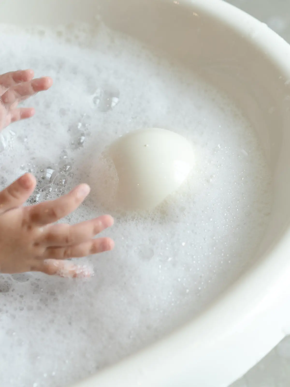 close up baby girl plays bubble in the water while bathing