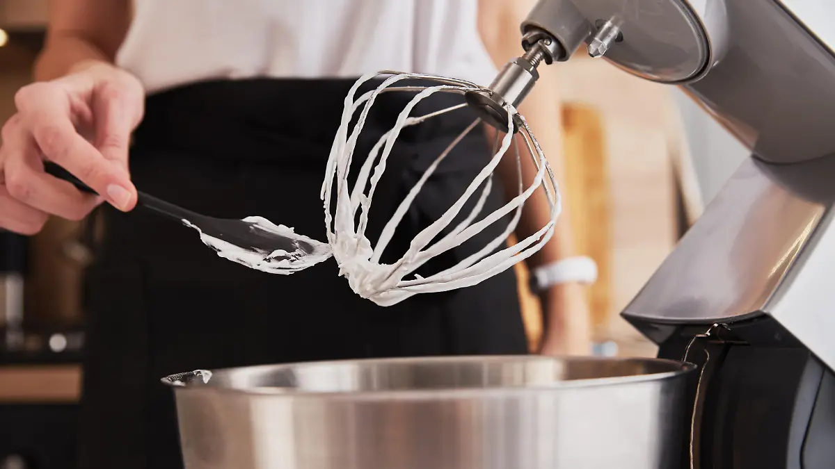 Frau schlägt Eischnee mit Rührmaschinen.