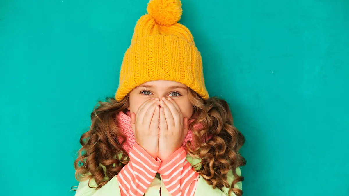 Little cute amazed girl wearing warm cap and scarf feeling cold