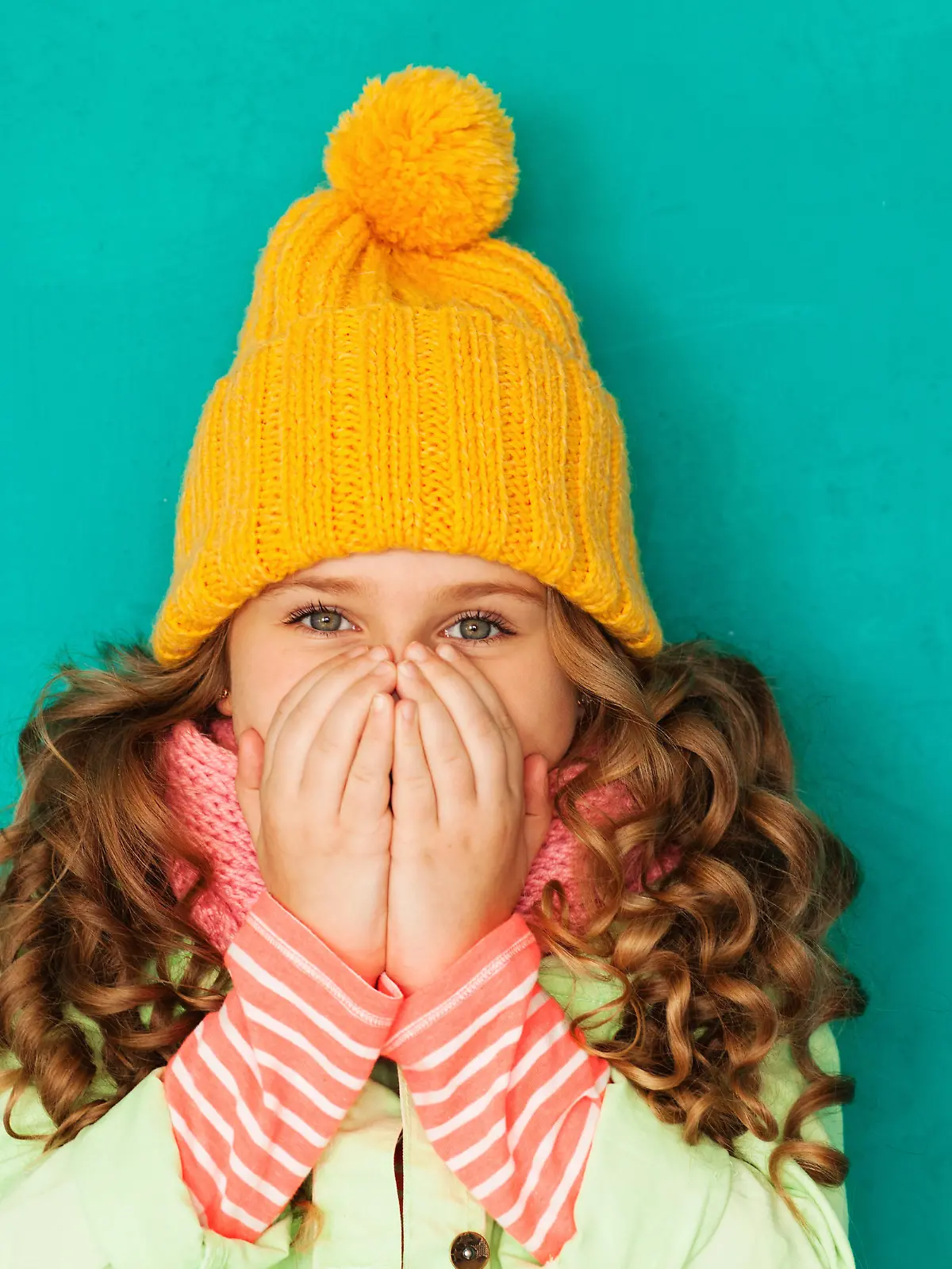 Little cute amazed girl wearing warm cap and scarf feeling cold