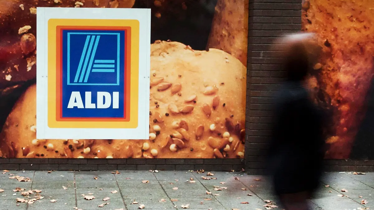 ARCHIV - 29.09.2014, Großbritannien, London: Eine Frau geht an einem Aldi-Supermarkt in London vorbei. Bis Ende 2021 will der Lebensmittel-Discounter Aldi in Großbritannien trotz unsicherer Brexit-Aussichten 100 neue Filialen eröffnen. (Zu dpa "Aldi will trotz Brexits in Großbritannien 100 neue Filialen eröffnen") Foto: Will Oliver/epa/dpa +++ dpa-Bildfunk +++