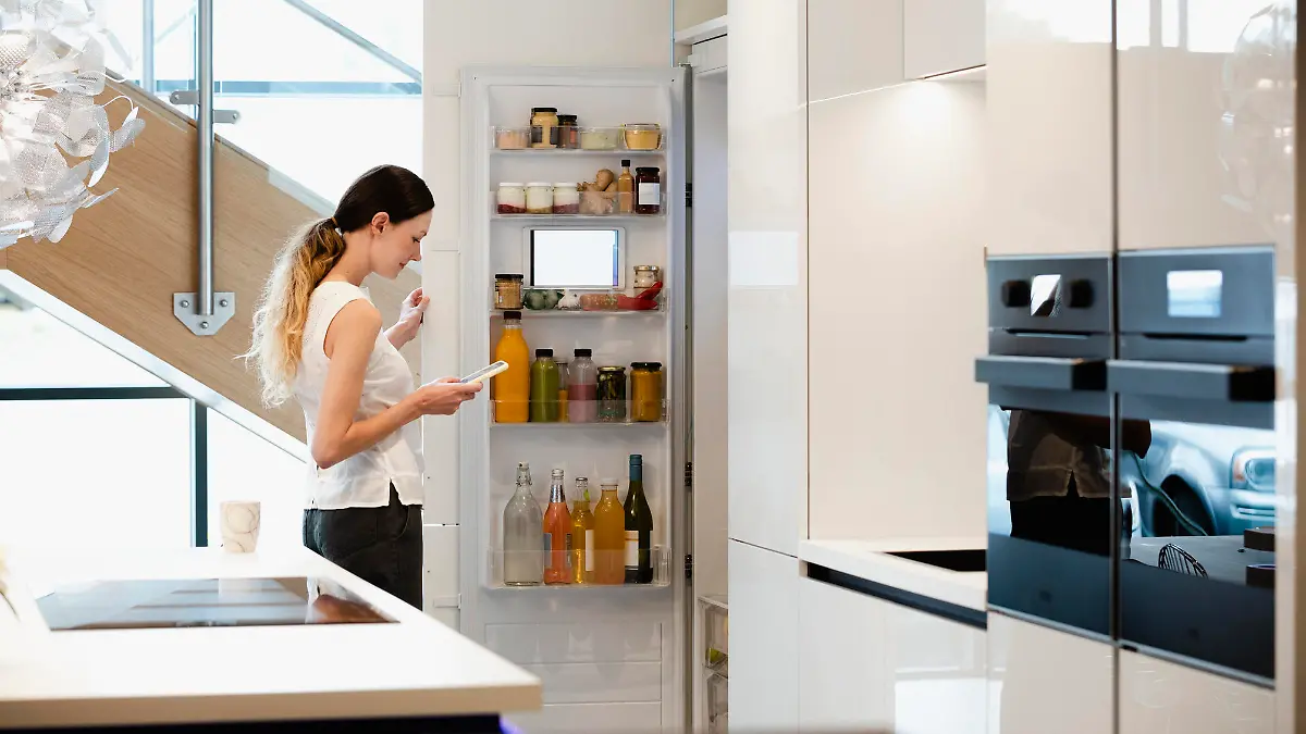 A side-view shot of a caucasian woman choosing what healthy snack to get out of her smart fridge.