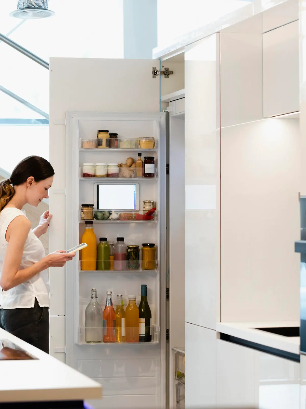 A side-view shot of a caucasian woman choosing what healthy snack to get out of her smart fridge.