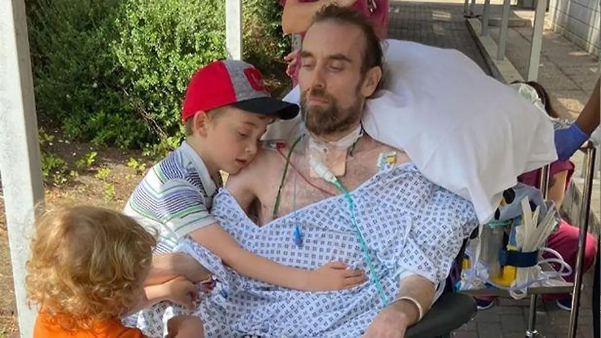 Familienvater Andrew Watts mit seinen beiden Kinder in einem Krankenhausbett