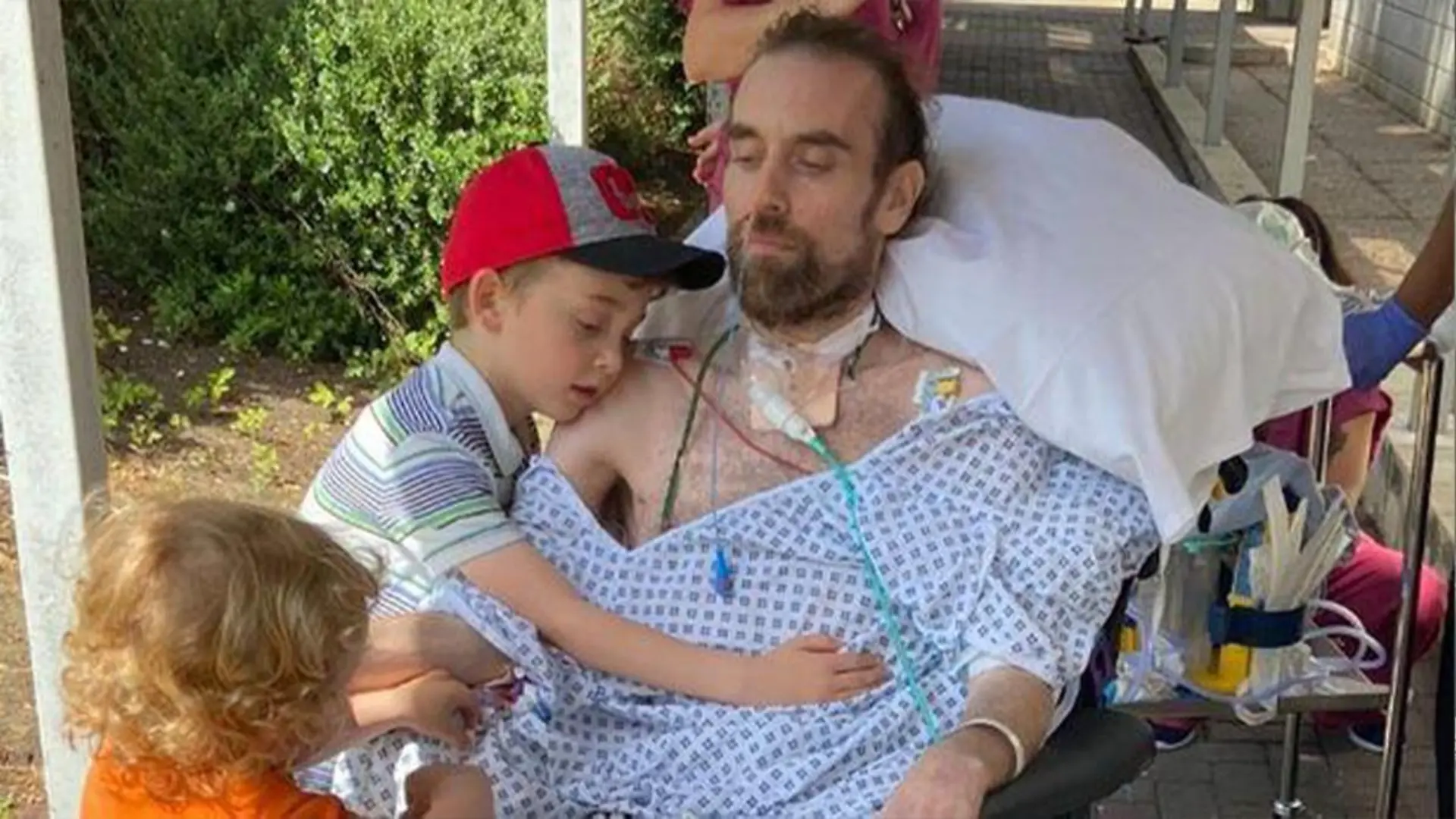 Familienvater Andrew Watts mit seinen beiden Kinder in einem Krankenhausbett
