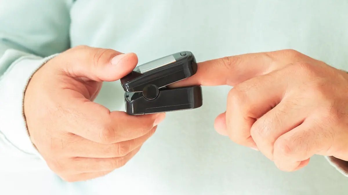 Man checking blood oxygen level with pulse oximeter at home. Health control concept