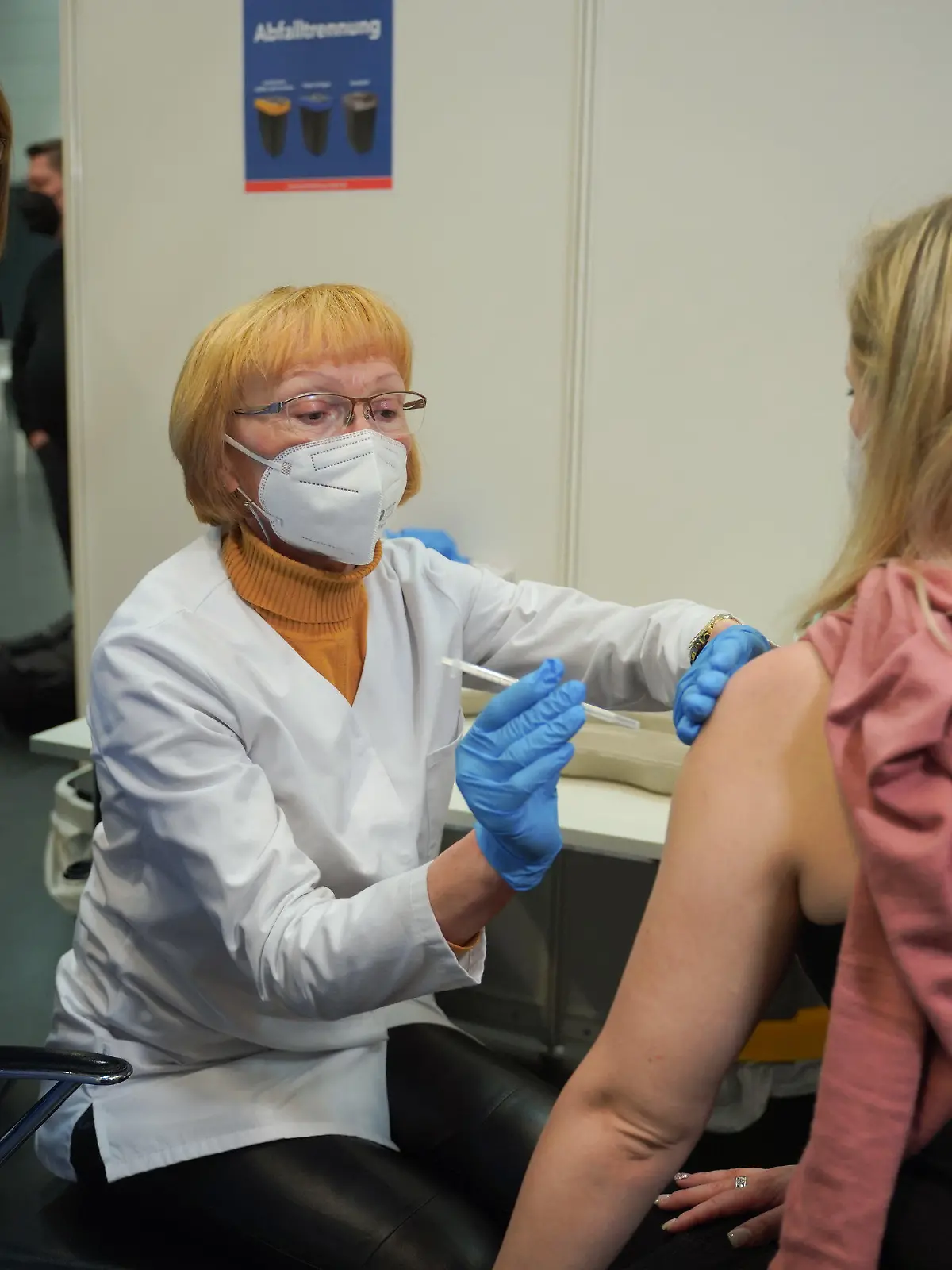 18.01.2022, Brandenburg, Potsdam: Ursula Nonnemacher (2.v.l, Bündnis90/Die Grünen), Brandenburgs Gesundheitsministerin, sieht dabei zu, wie die Apothekerin Barbara Oberüber (2.v.r) einer Frau in der Impfstelle Metropolishalle eine Corona-Impfung erklärt, während die Ärztin Bushra Malik ihr beratend zur Seite steht. In Brandenburg starten in dieser Woche die Schulungen von Apothekerinnen und Apotheker zur Corona-Impfung. Foto: Joerg Carstensen/dpa +++ dpa-Bildfunk +++