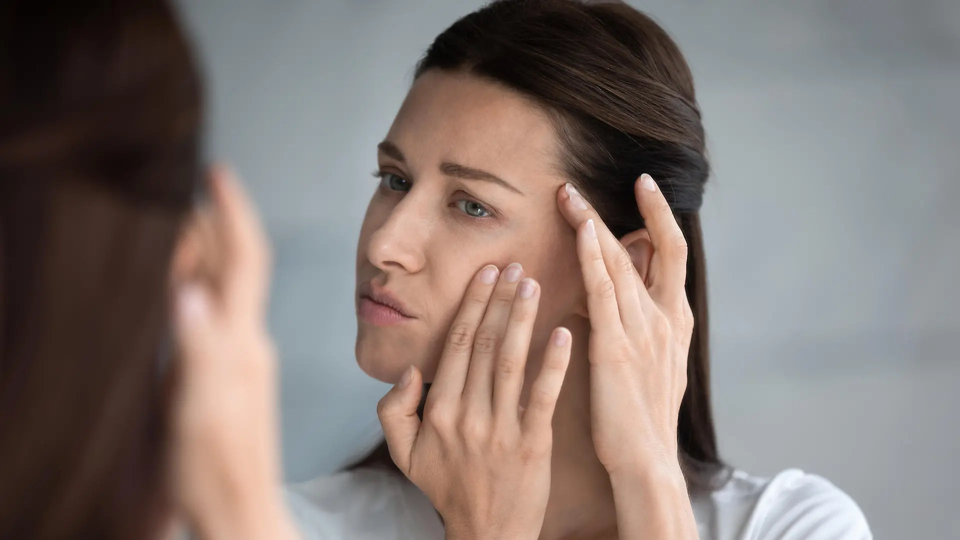 Close up reflection 35s woman touches face skin looks at mirror feeling worried about first wrinkles and age-related changes derma problems. Cosmetic facial plastic surgery skincare treatments concept