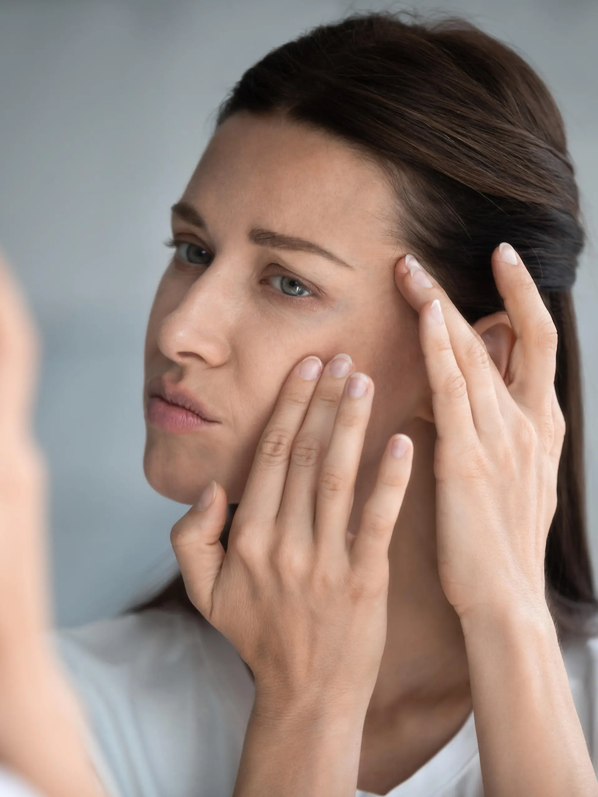 Close up reflection 35s woman touches face skin looks at mirror feeling worried about first wrinkles and age-related changes derma problems. Cosmetic facial plastic surgery skincare treatments concept