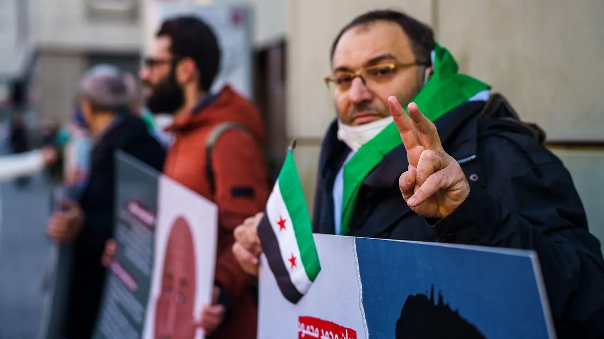 19.01.2022, Hessen, Frankfurt/Main: Ein syrischer Aktivist macht vor dem Gerichtsgebäude das ·Victory-Zeichen·. Vor dem Oberlandesgericht beginnt am Mittwoch ein weiterer Prozess wegen Verbrechen gegen die Menschlichkeit im Bürgerkriegsland Syrien. Angeklagt ist ein 36-jähriger Arzt. Die Bundesanwaltschaft wirft ihm Folter und die vorsätzliche Tötung eines Gefangenen vor. Er soll in den Jahren 2011 und 2012 in einem Armeekrankenhaus und einem Gefängnis des Militärgeheimdiensts in Homs Gefangenen schwere körperliche sowie seelische Schäden zugefügt haben. Foto: Andreas Arnold/dpa +++ dpa-Bildfunk +++