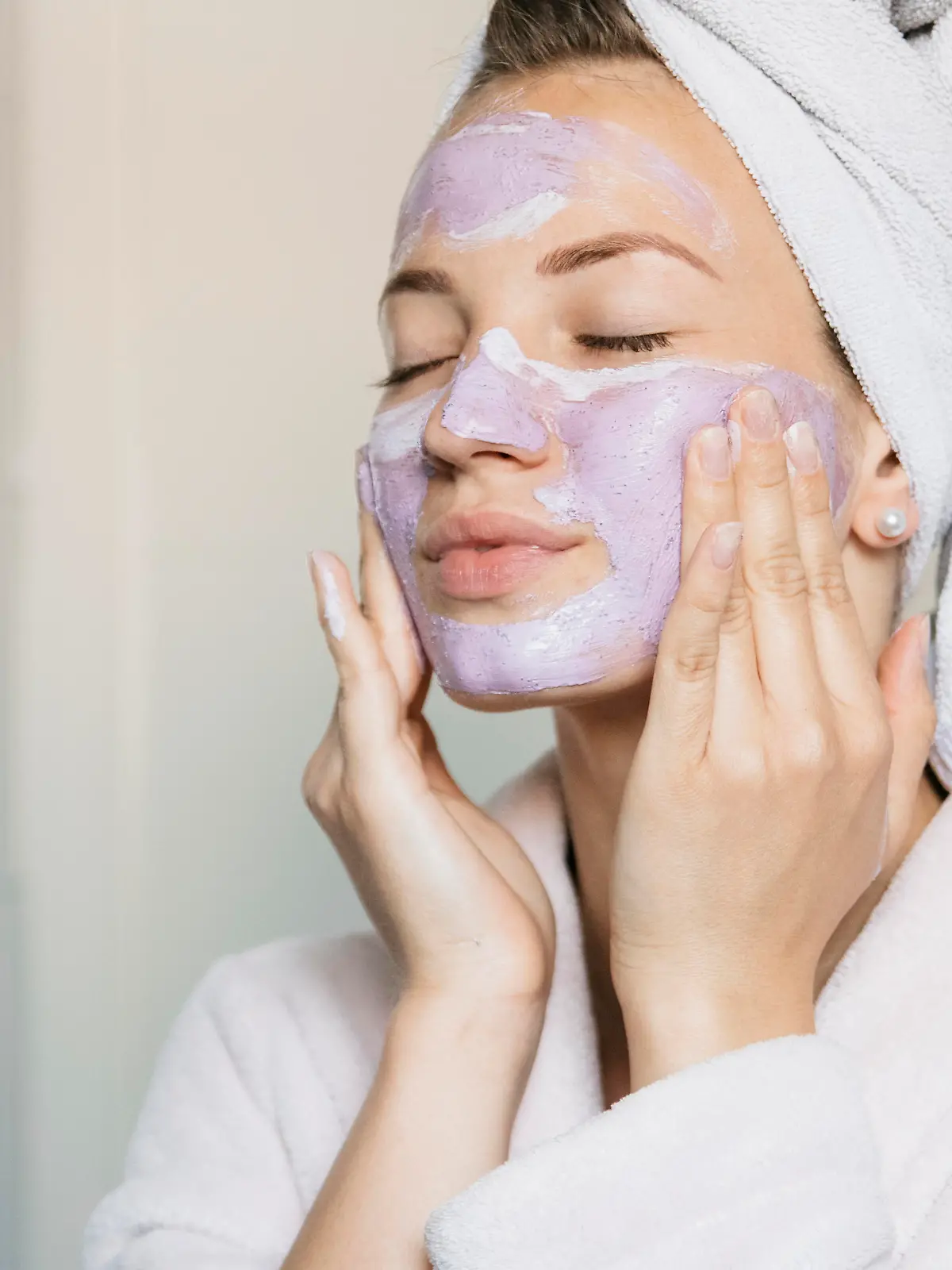 Attractive young woman putting on a beauty mask, applying it on her face