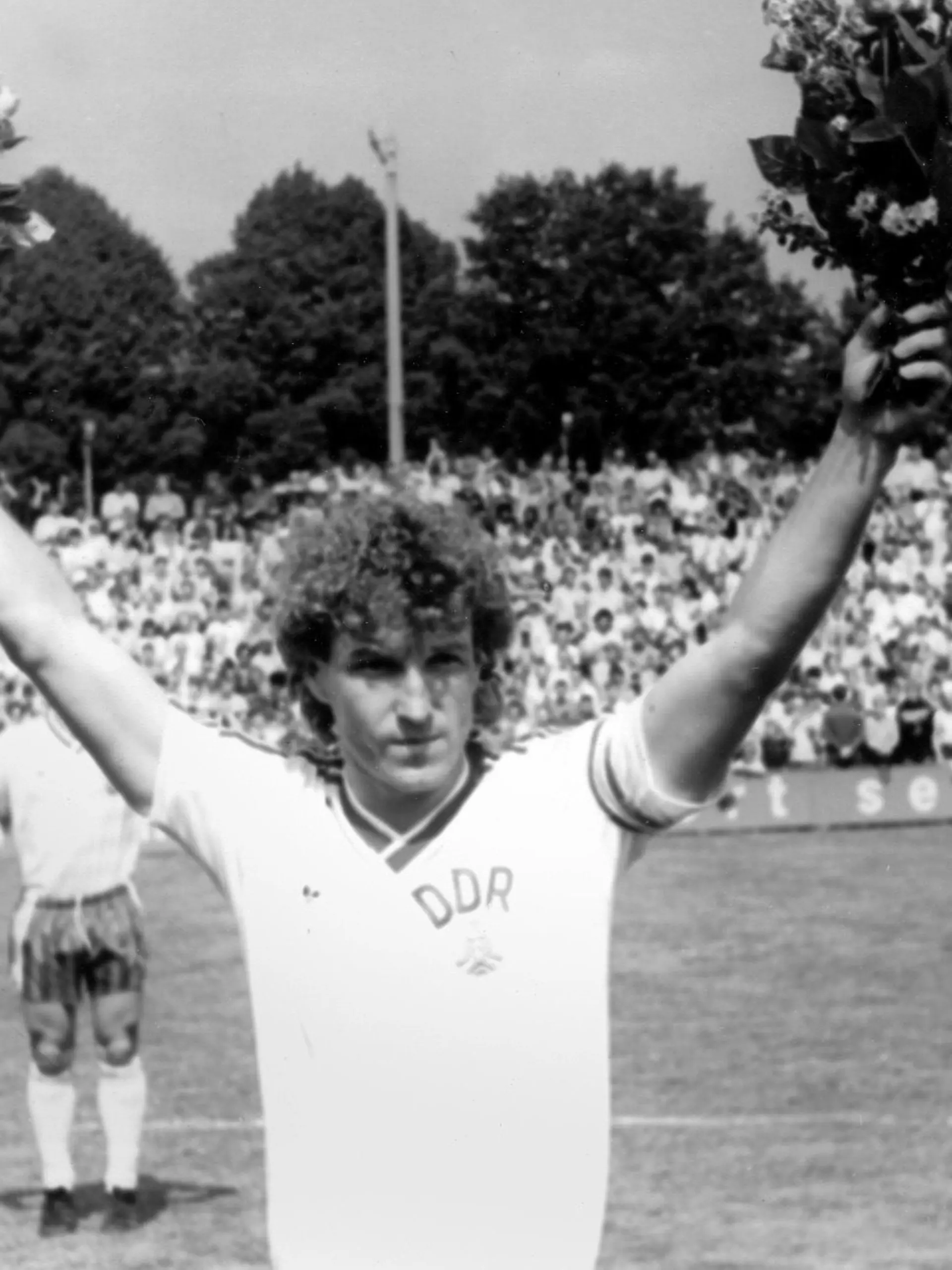 Hans-Jürgen "Dixie" Dörner, der Libero der DDR-Fußballnationalmannschaft, grüßt mit Blumen am 18.05.1985 im Potsdam-Babelsberger Karl-Liebknecht-Stadion ins Publikum. Er wird vor dem WM-Qualifikationsspiel gegen Luxemburg (3:1) vor 9.000 Zuschauern für sein 100. (und letztes) Länderspiel geehrt. Dörner kam zwischen 1969 und 1985 auf diese Zahl (9 Tore). Er spielte 19 Jahre für die Dresdner Dynamo-Mannschaft. Foto: Gert Kilian. +++(c) dpa - Report+++