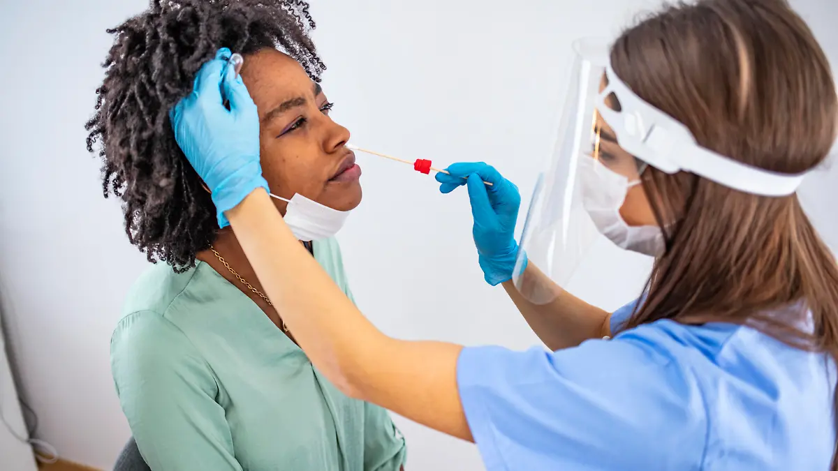 Shot of a doctor using cotton swab while doing coronavirus PCR test at the hospital. Doctor laboratory assistant takes swab from nose of sick patient. Coronavirus sample from female patient's nose or mouth.