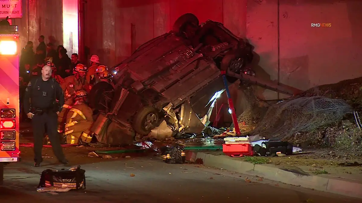 Emergency personnel work at the scene of a fatal accident after the vehicle plunged off an elevated section of Interstate 210 landing below on Michillinda Ave., just south of Foothill Blvd., in Pasadena, Calif., late Sunday, Jan. 16, 2022. Two people in the car died at the scene and the third died at a hospital, KABC-TV reported. (AP Photo/James Carbone)
