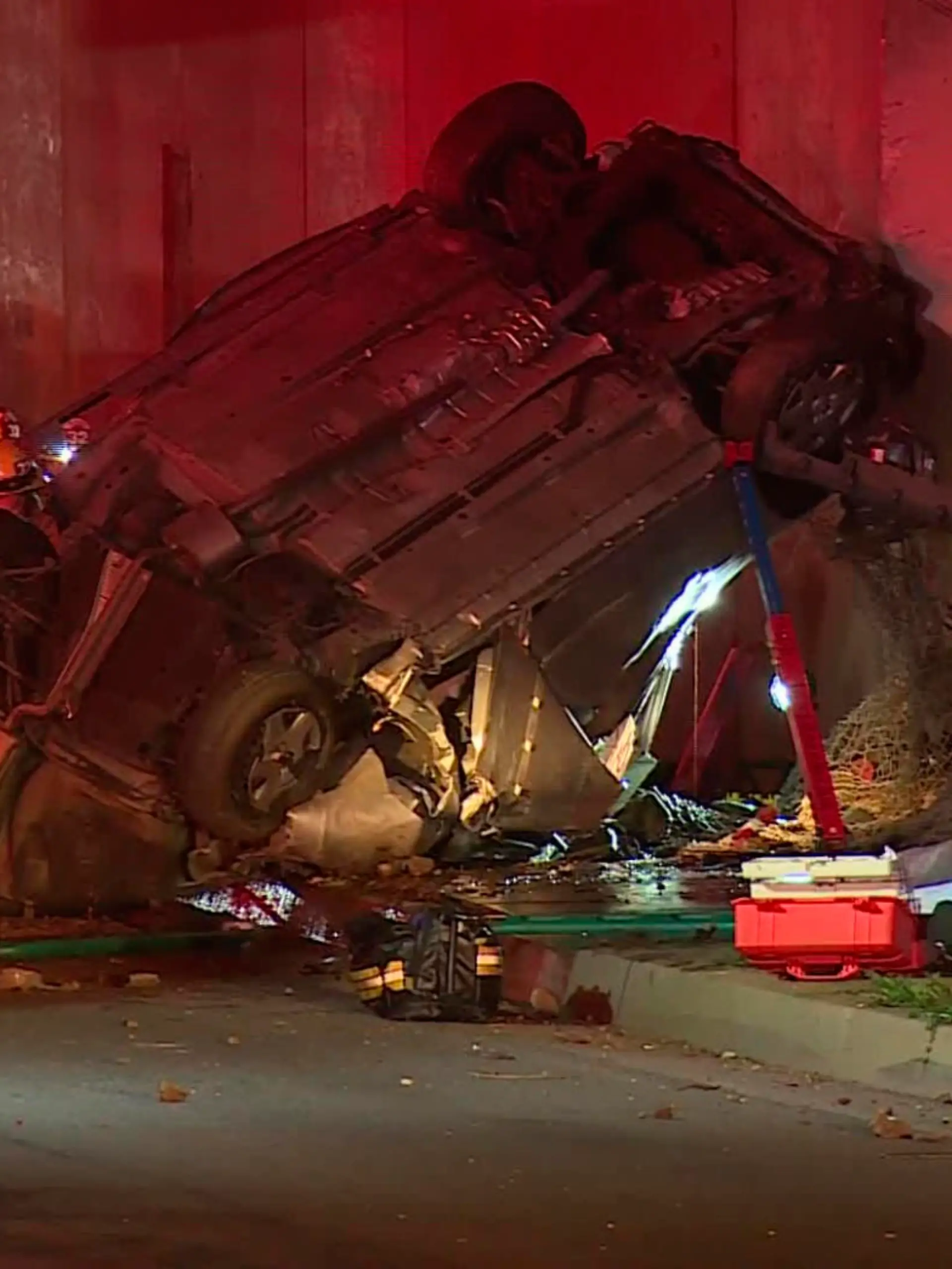 Emergency personnel work at the scene of a fatal accident after the vehicle plunged off an elevated section of Interstate 210 landing below on Michillinda Ave., just south of Foothill Blvd., in Pasadena, Calif., late Sunday, Jan. 16, 2022. Two people in the car died at the scene and the third died at a hospital, KABC-TV reported. (AP Photo/James Carbone)