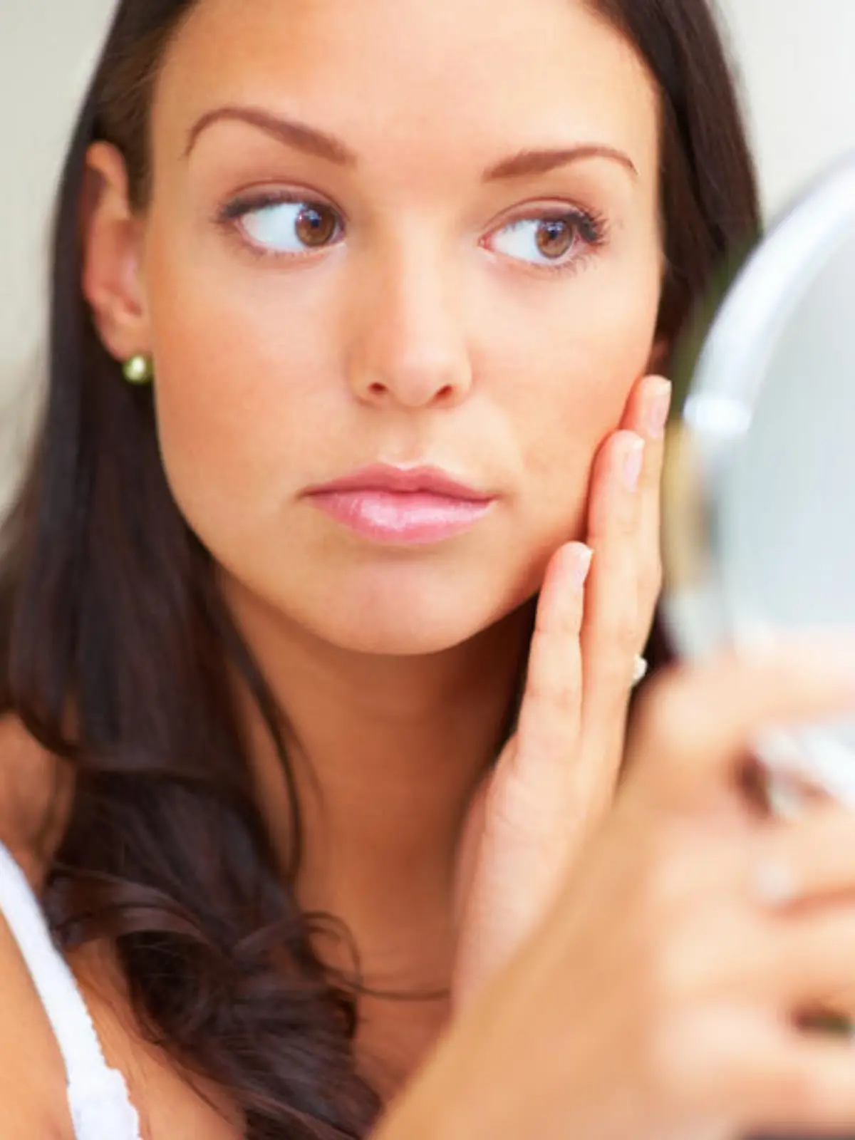 Closeup portrait of young woman holding a mirror