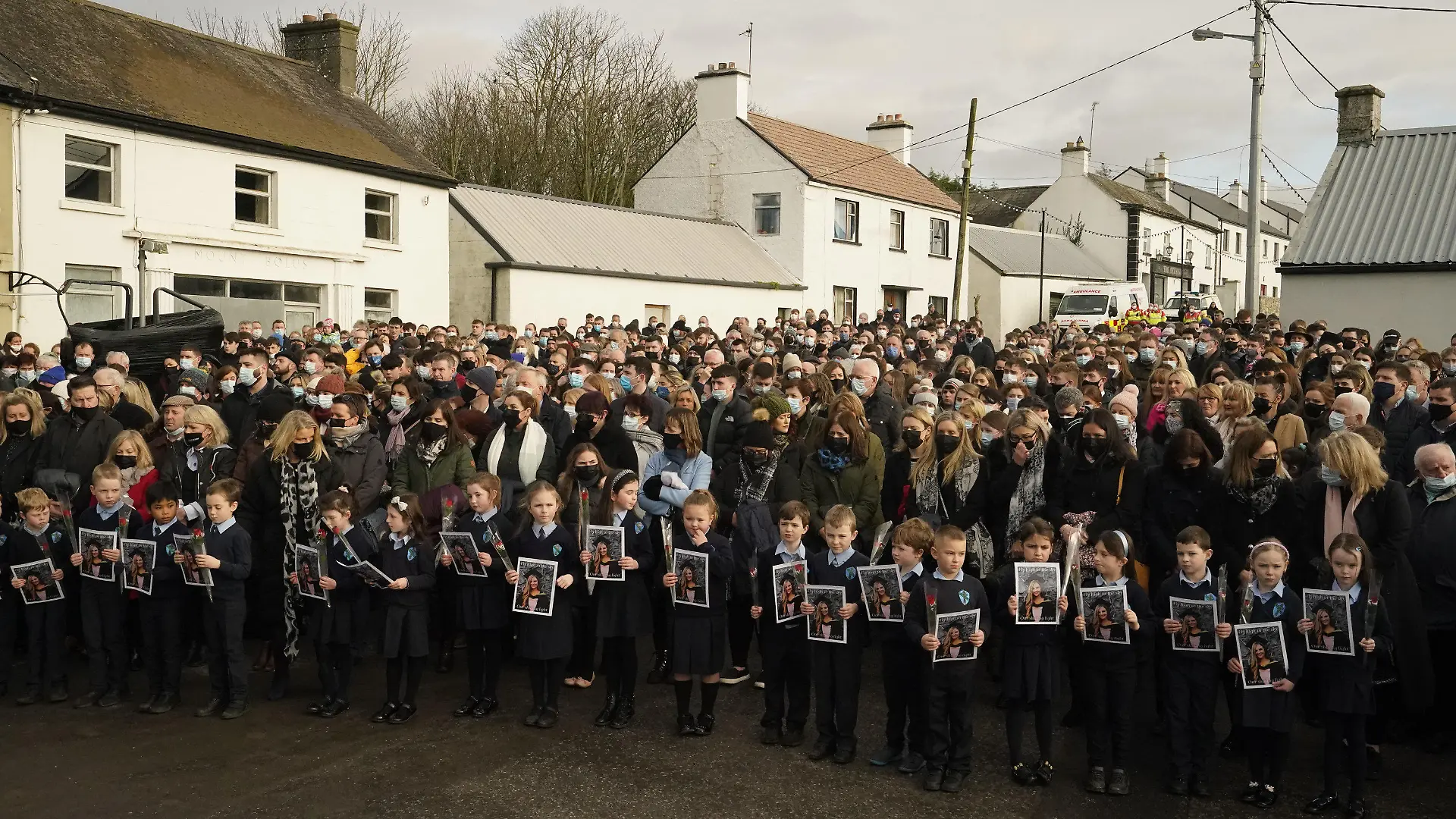 18.01.2022, Irland, Mountbolus: Schülerinnen, Schüler und weitere Trauergäste halten rote Rosen und Fotos bei der Trauerfeier für die in Irland getötete Lehrerin Ashling Murphy. Unter großer Anteilnahme ist die in Irland getötete Lehrerin Ashling Murphy beigesetzt worden. Die 23-Jährige war am 12.01.2022 beim Joggen an einem Kanal in der Kleinstadt Tullamore getötet worden. Foto: Niall Carson/PA Wire/dpa +++ dpa-Bildfunk +++