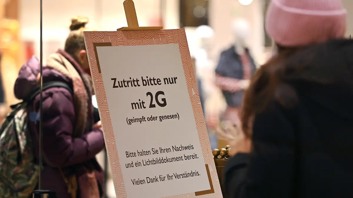 Kontrolle der 2G Regel im Einzelhandel in Bayern. Ein Schild am Eingang eines Geschaeftes weist auf die 2G Regel hin.Einlass nur mit FFP2 Maske und 2g Nachweis,Impfnachweis und Ausweisdokument bereithalten, Eintritt nur fuer geimpfte oder genesene Kunden,Personen, Impfnachweis und Personalausweis bereithalten. Smartphone,Handy.