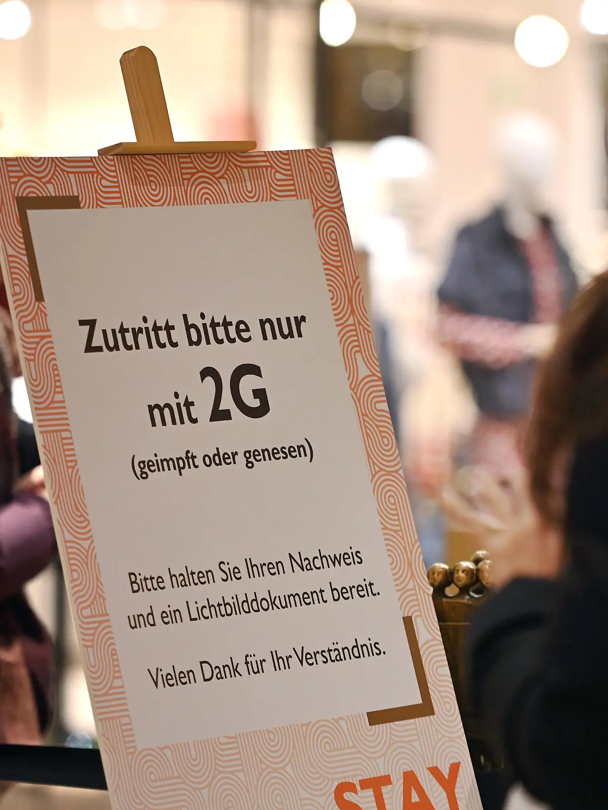 Kontrolle der 2G Regel im Einzelhandel in Bayern. Ein Schild am Eingang eines Geschaeftes weist auf die 2G Regel hin.Einlass nur mit FFP2 Maske und 2g Nachweis,Impfnachweis und Ausweisdokument bereithalten, Eintritt nur fuer geimpfte oder genesene Kunden,Personen, Impfnachweis und Personalausweis bereithalten. Smartphone,Handy.
