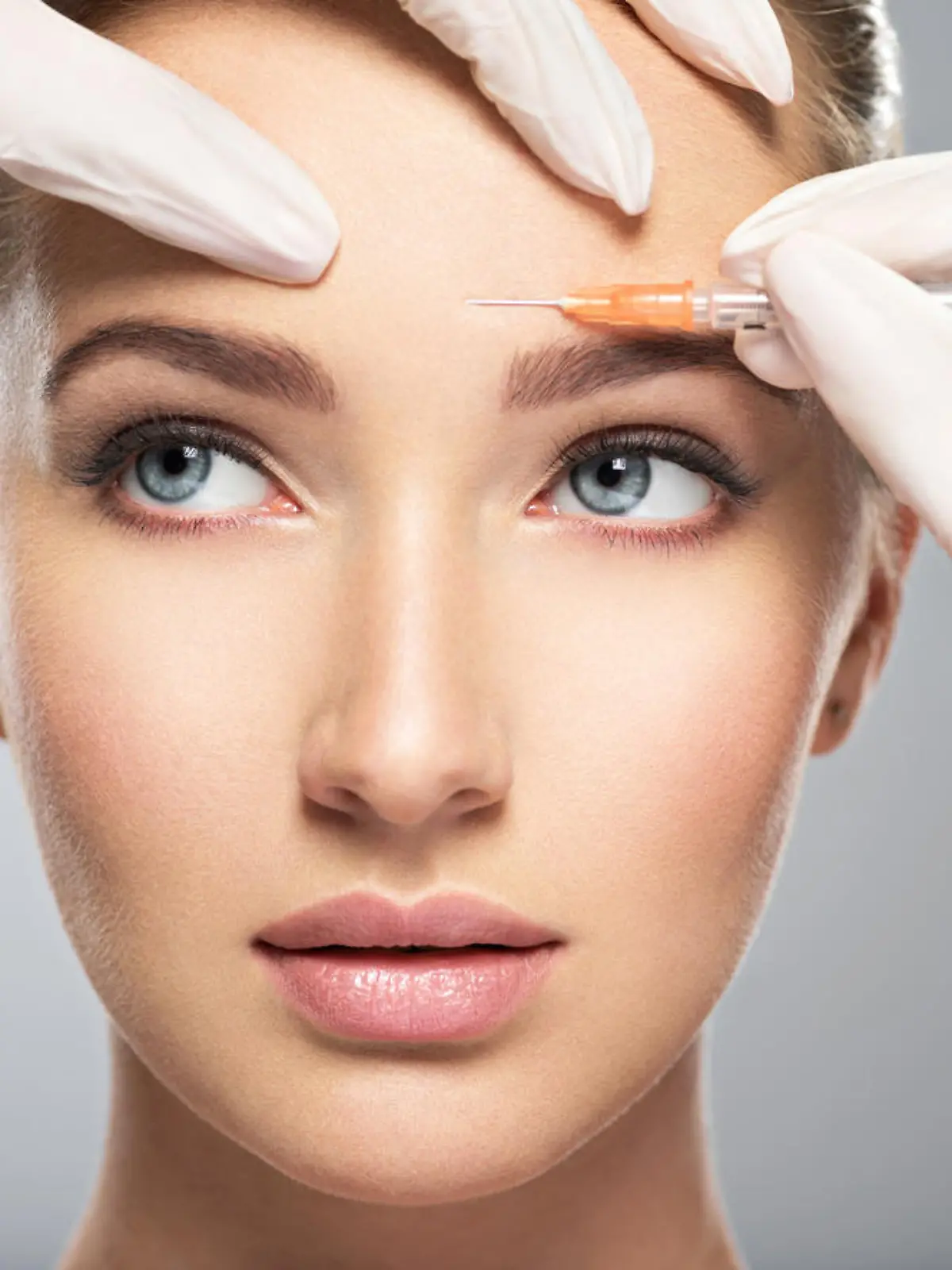 Portrait of young Caucasian woman getting botox cosmetic injection in forehead. Beautiful woman gets botox injection in her face.