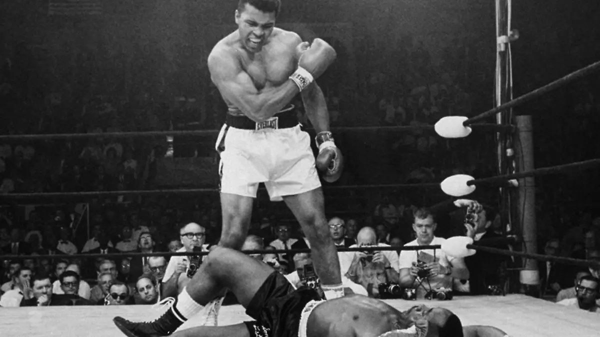 FILE - In this May 25, 1965, file photo, heavyweight champion Muhammad Ali stands over fallen challenger Sonny Liston, shouting and gesturing shortly after dropping Liston with a short hard right to the jaw in the first round of their title fight in Lewiston, Maine. The bout produced one of the strangest finishes in boxing history as well as one of sports¿ most iconic moments. (AP Photo/John Rooney, File) |